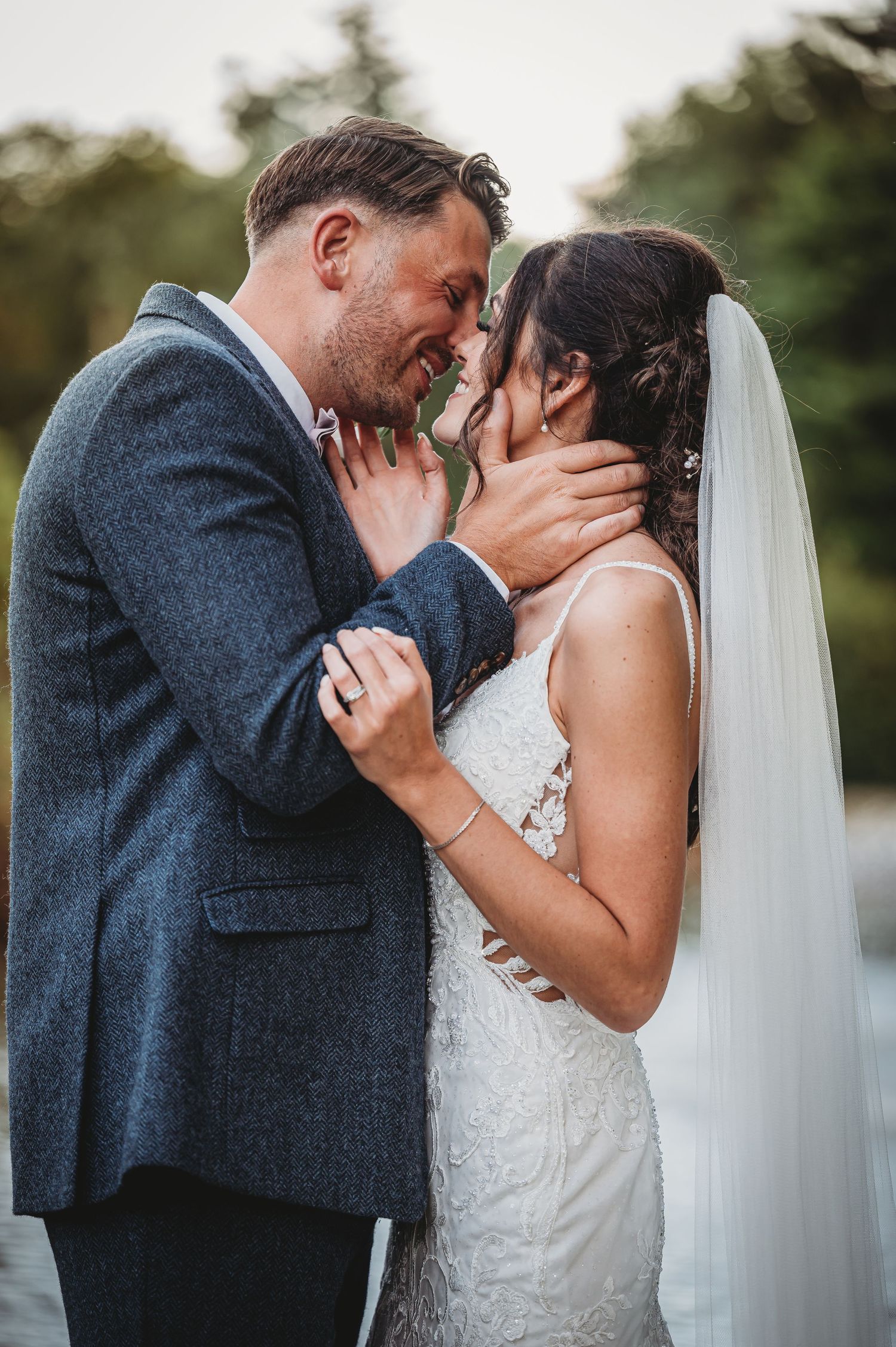 A romantic moment captured between newlyweds sharing an intimate embrace outdoors in their wedding attire.