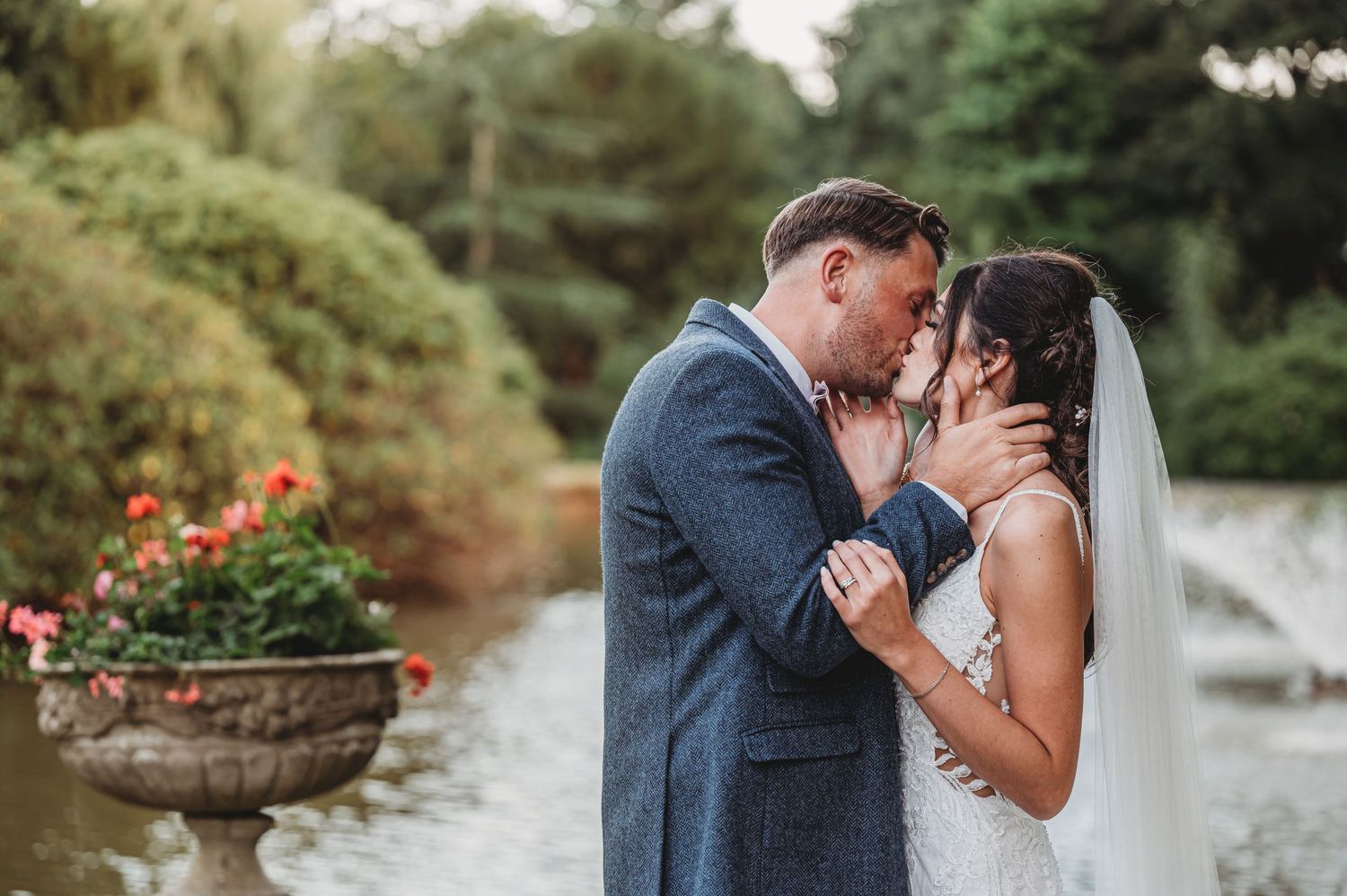 A tender moment between newlyweds in a garden setting with decorative planters and greenery in the background.