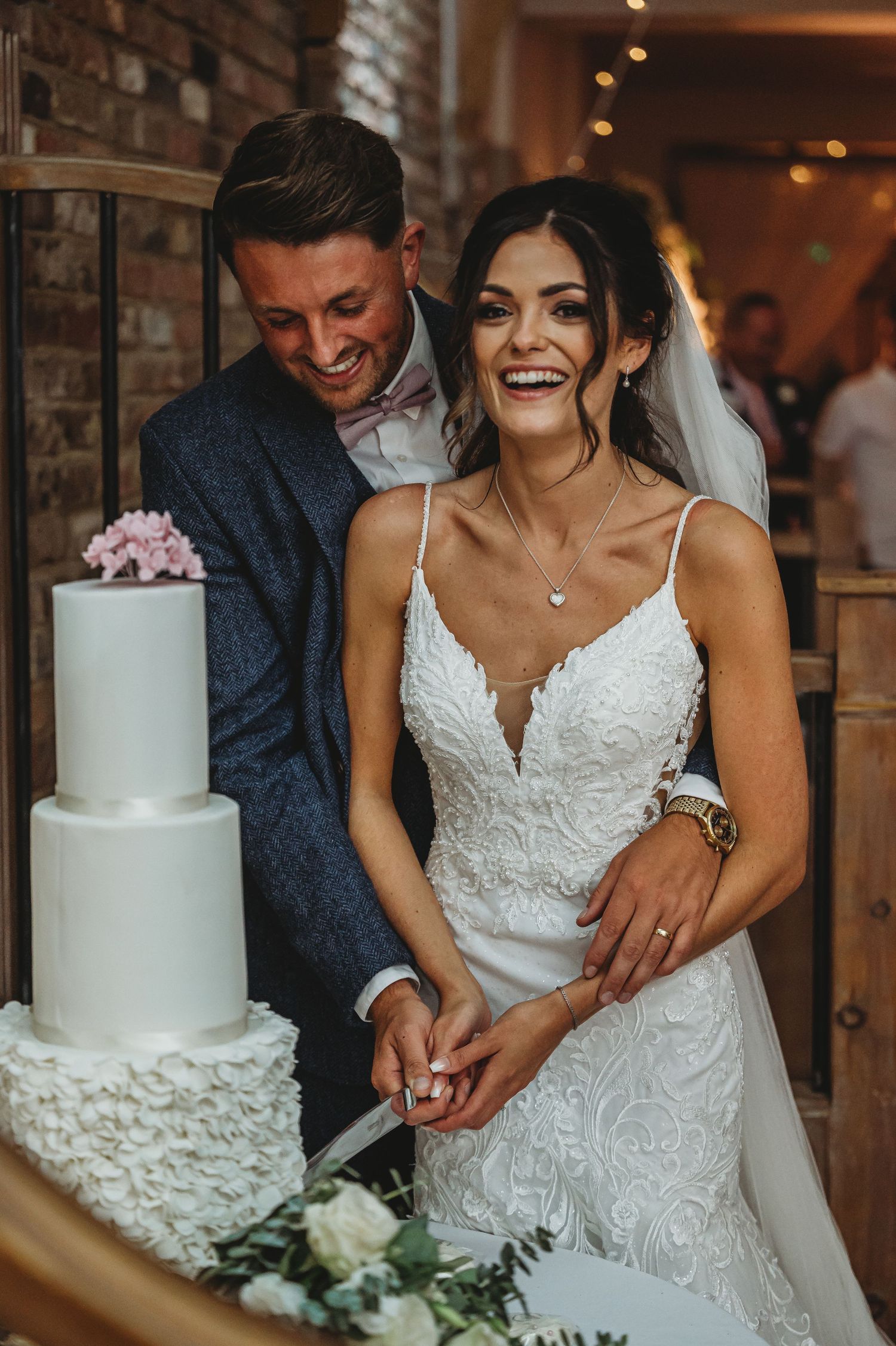 Newlyweds share a joyful moment while cutting their elegant white wedding cake together.