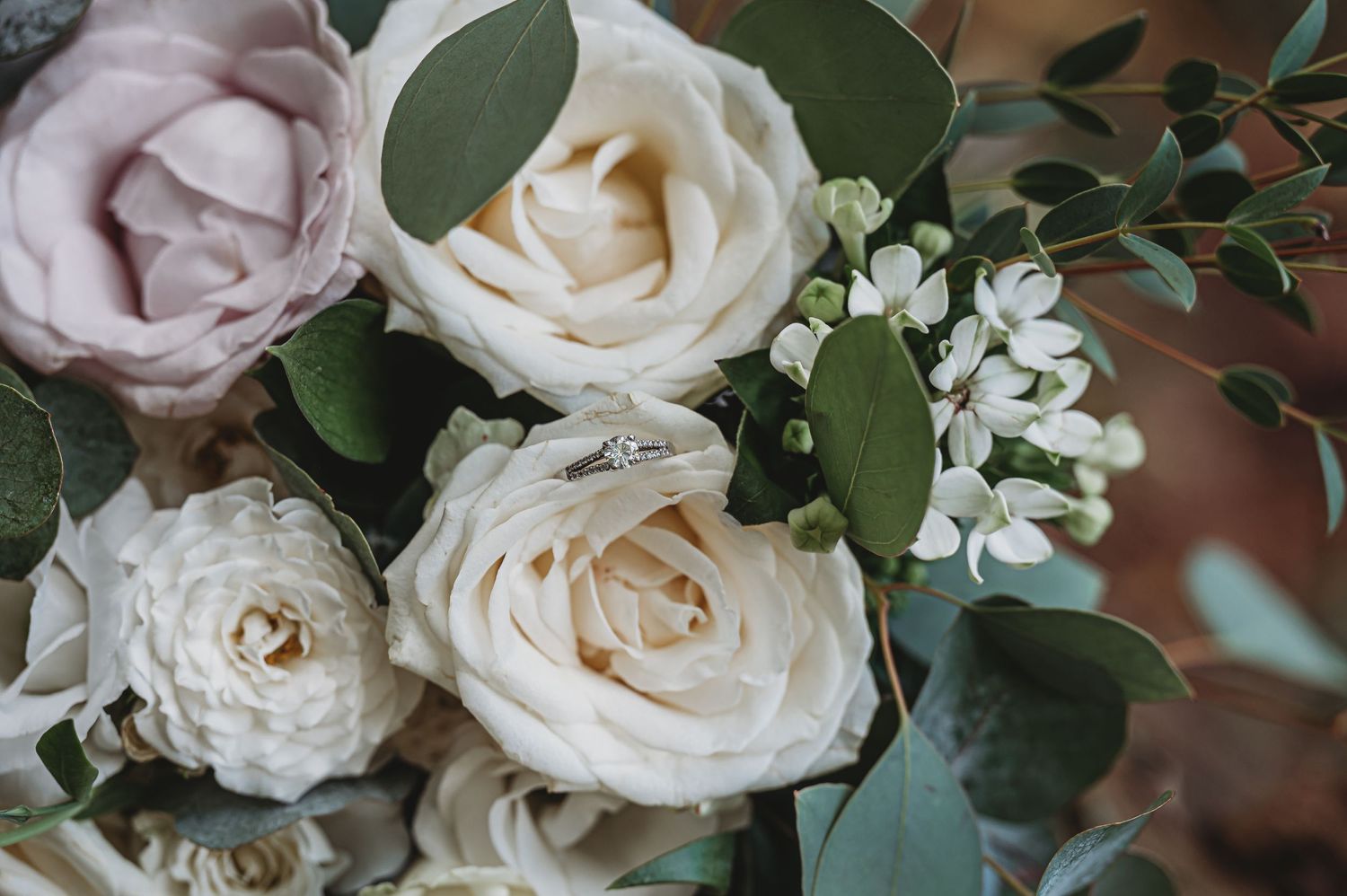 Close-up of an elegant floral arrangement featuring cream and blush roses with eucalyptus greenery against blur background.