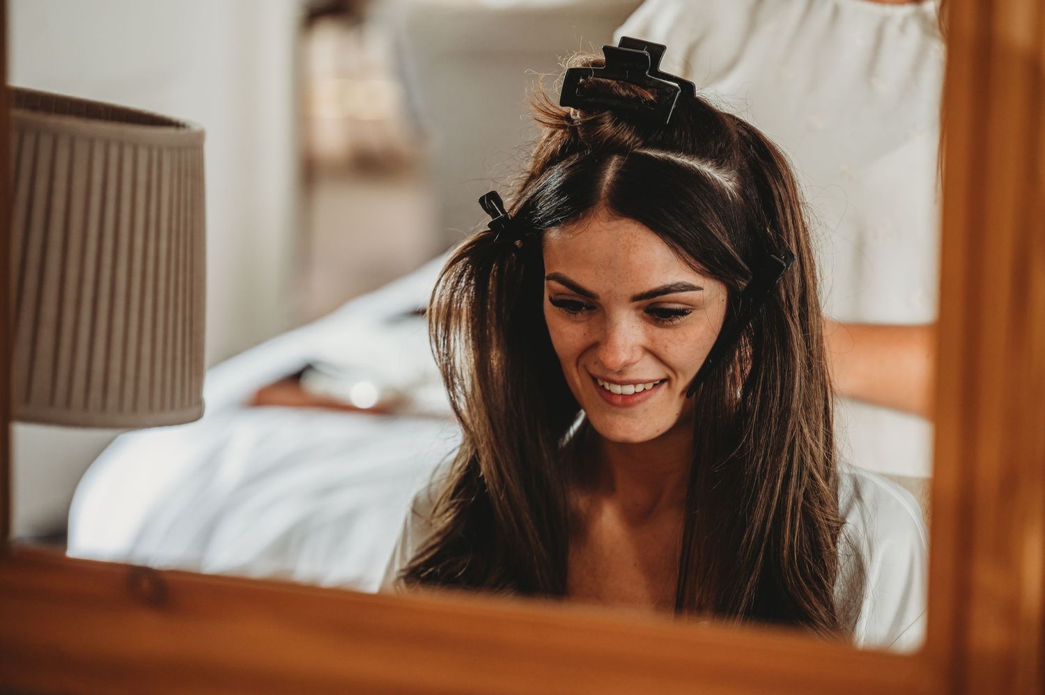 Dark haired woman getting ready with styling tools in relaxed bedroom setting.