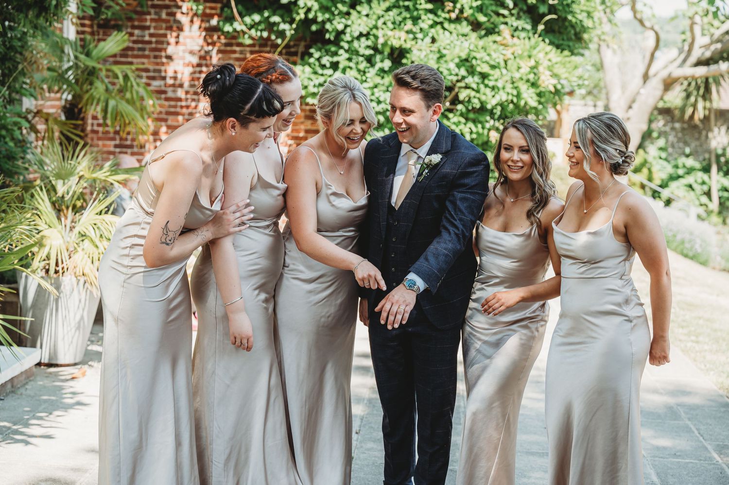 Wedding party in formal attire posing in a garden setting.