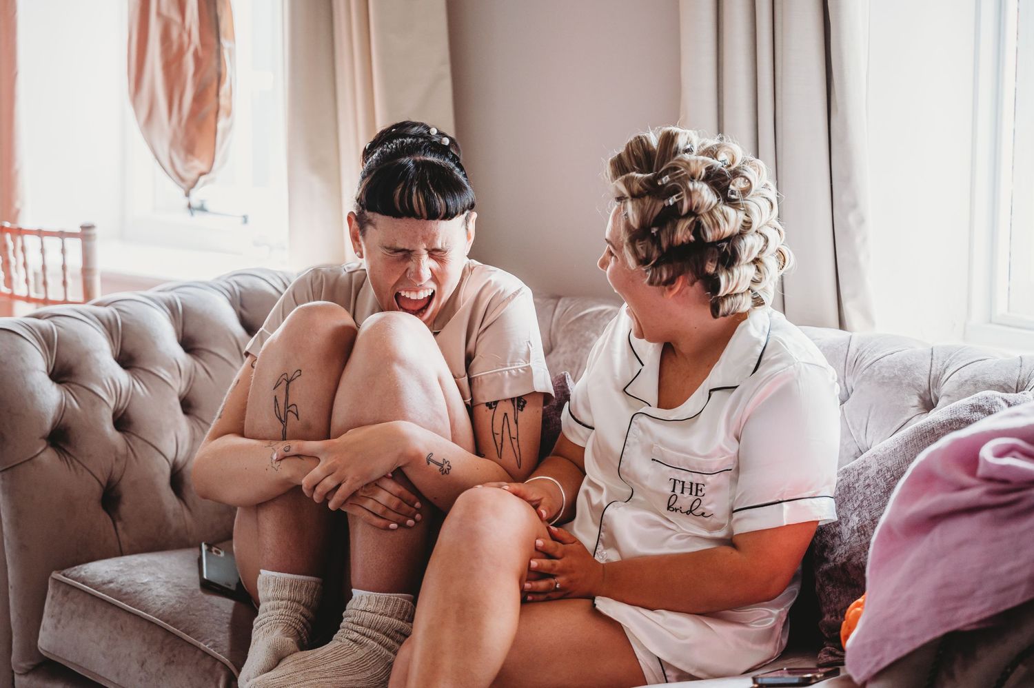 Two people sharing an emotional and touching candid moment while sitting on a grey couch.