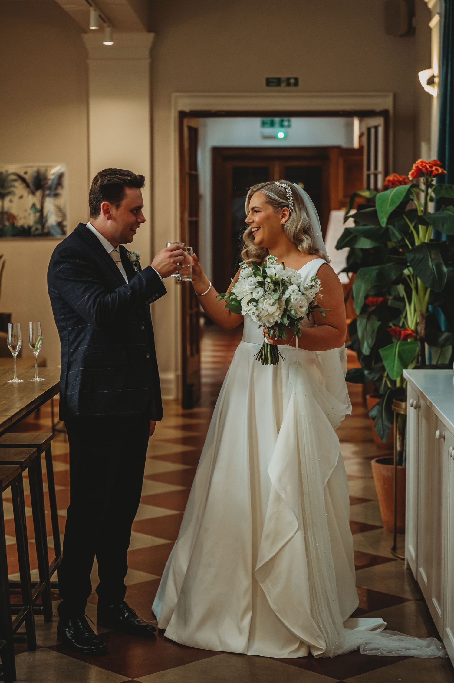 A couple shares an intimate moment at their indoor wedding, with the bride in a flowing white gown holding a bouquet.