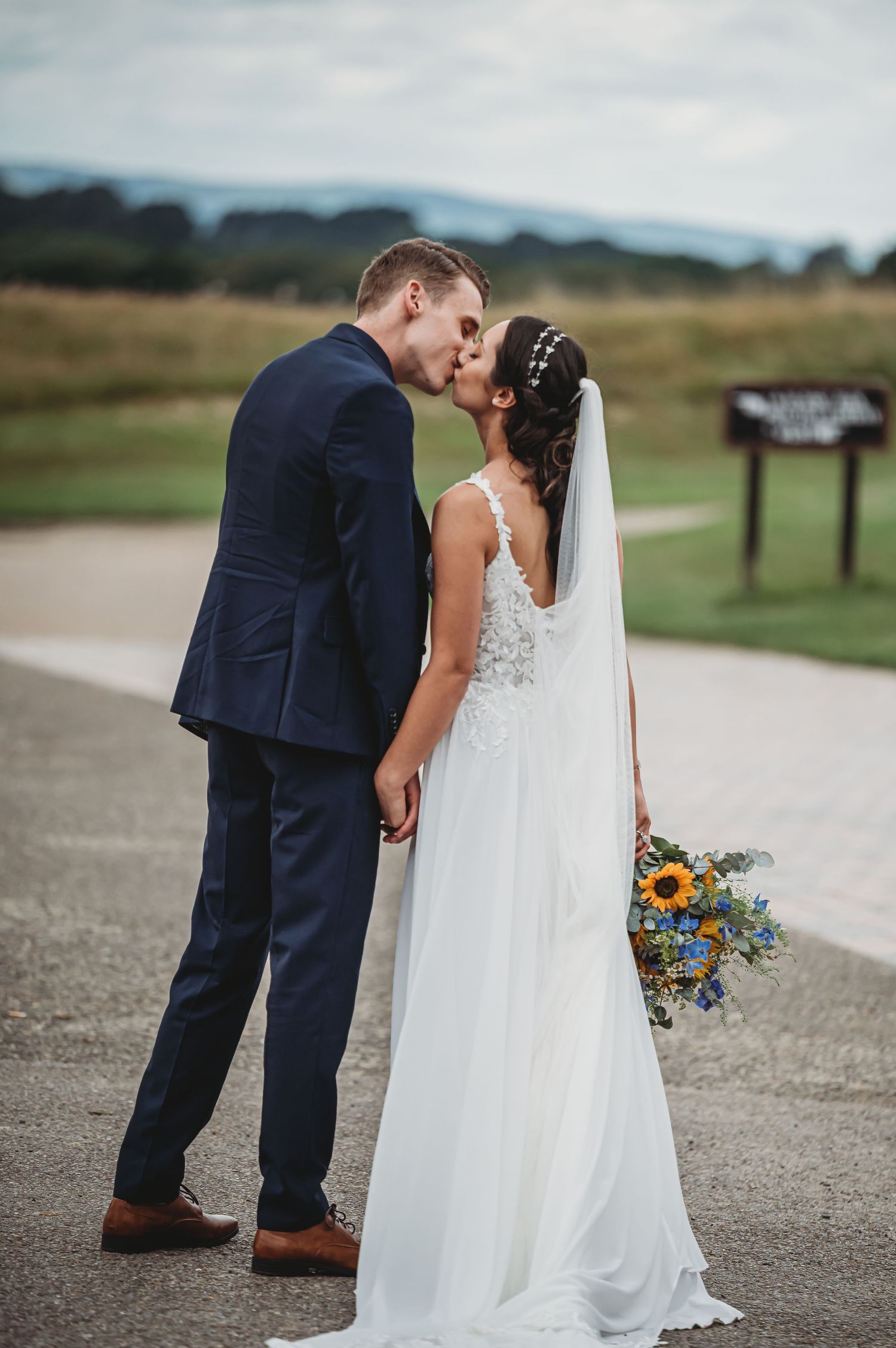A couple shares a romantic moment on their wedding day as the bride holds a colorful wildflower bouquet.
