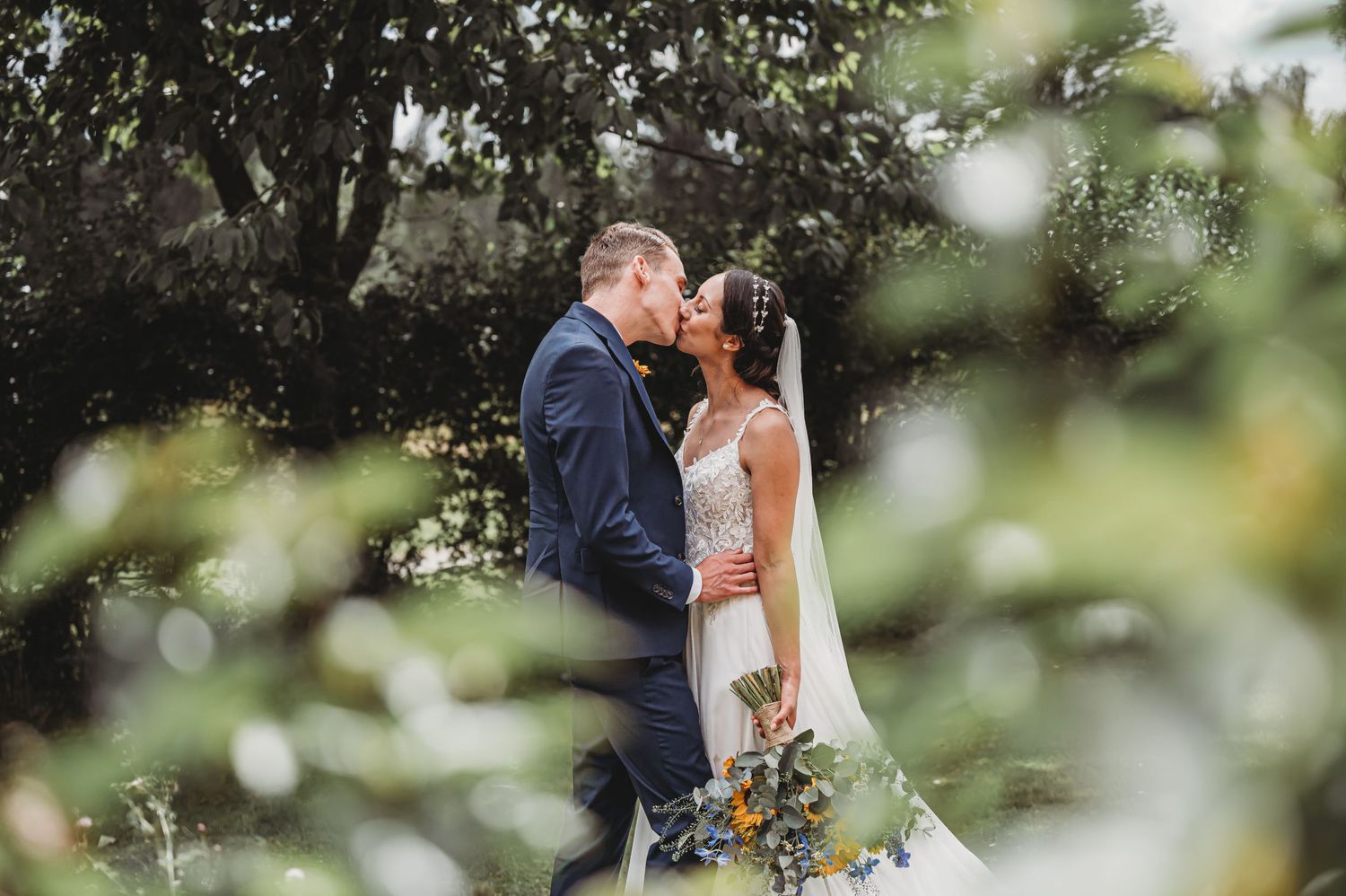 Newlyweds share an intimate moment together in a lush garden setting.