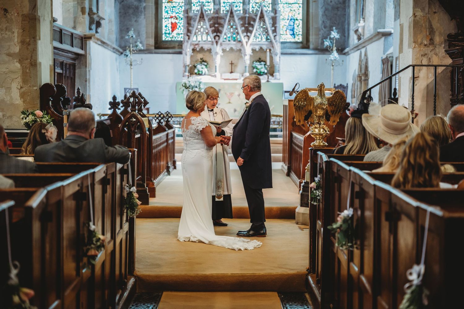 A traditional wedding ceremony takes place in a quaint old church with rustic wooden pews and stained glass windows.