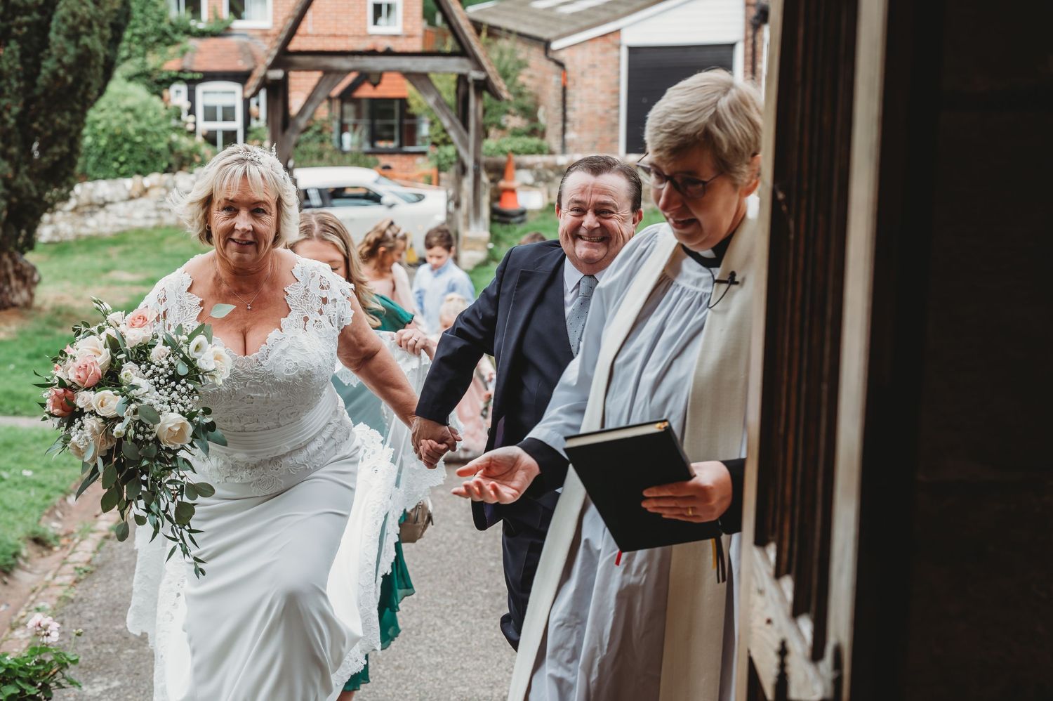 People walking down a garden path during an outdoor wedding ceremony at a brick building.