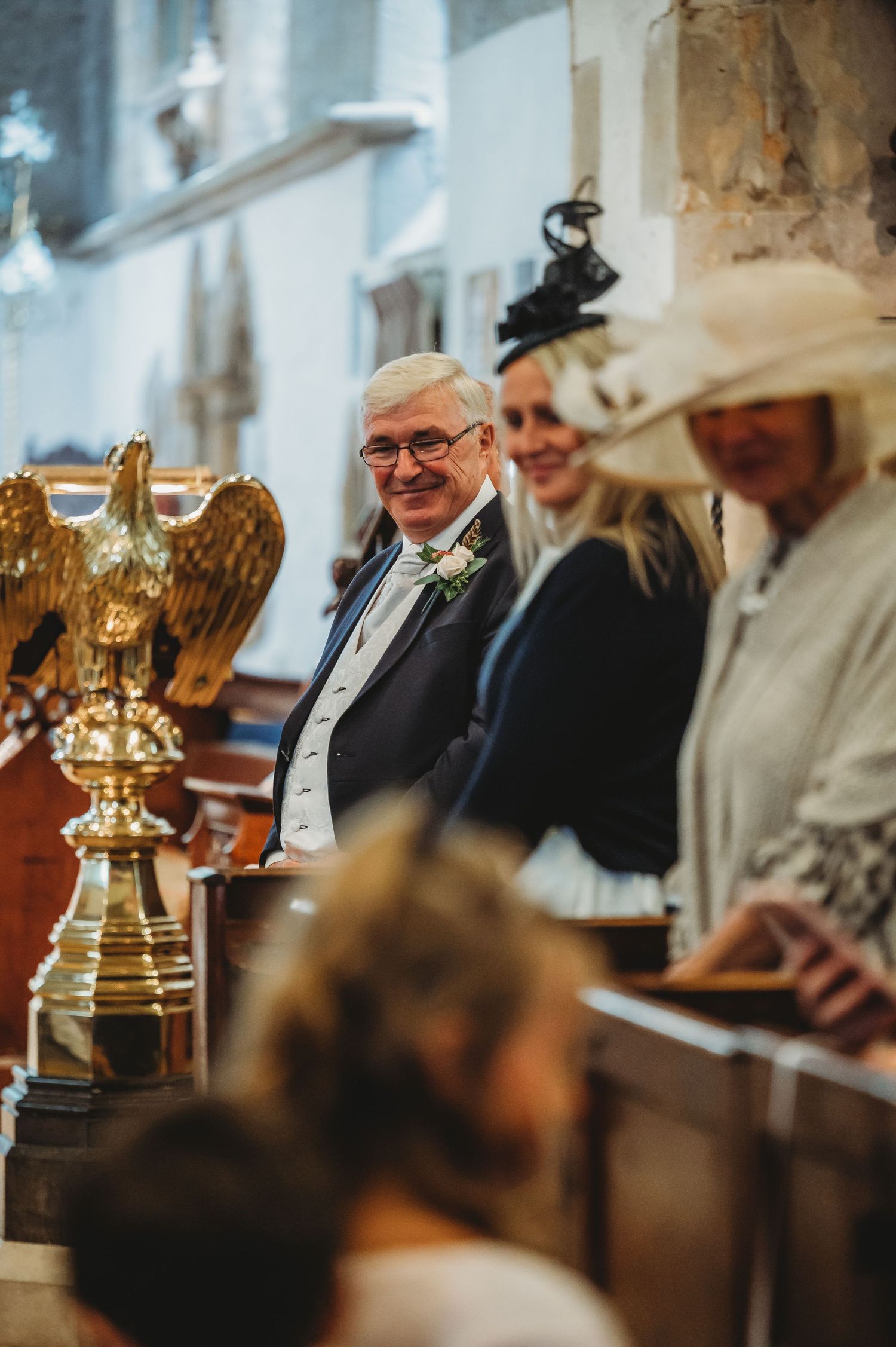Elegant church gathering with attendees in formal attire beside a golden decorative eagle lectern.