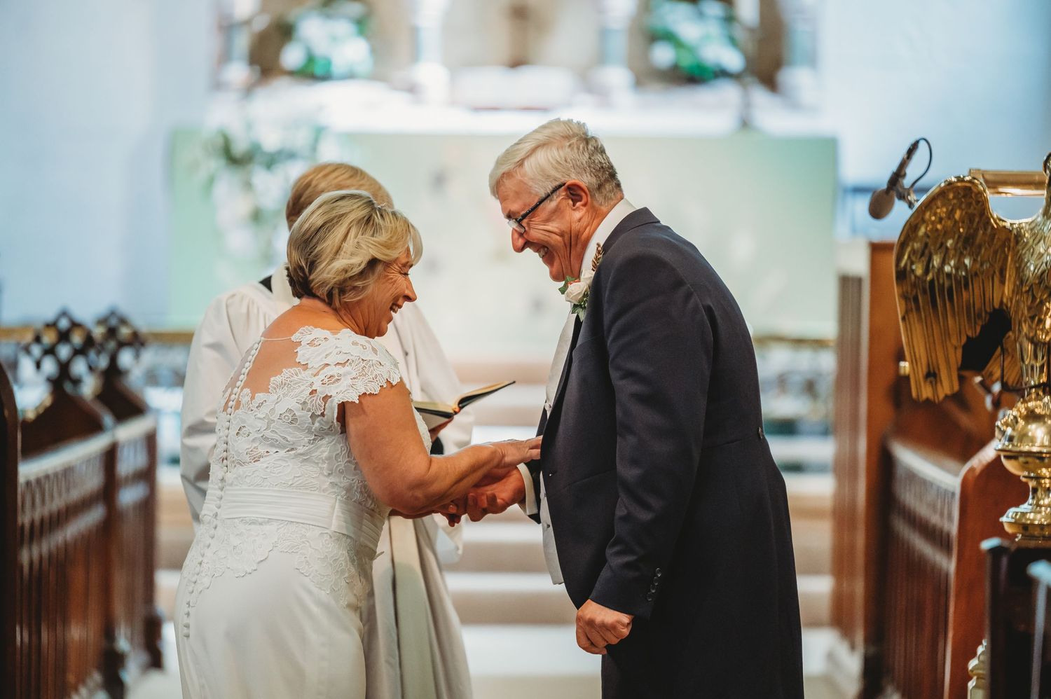 An intimate moment is shared during a church wedding ceremony among wooden church pews.