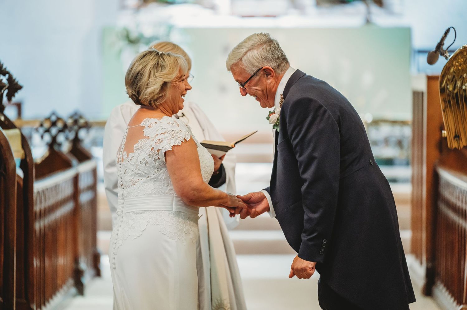 A tender moment unfolds during a wedding ceremony in a church as a couple exchanges rings at the altar.