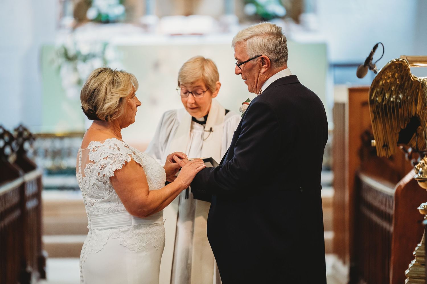 A couple exchanges vows during an intimate wedding ceremony inside a church with a minister officiating.