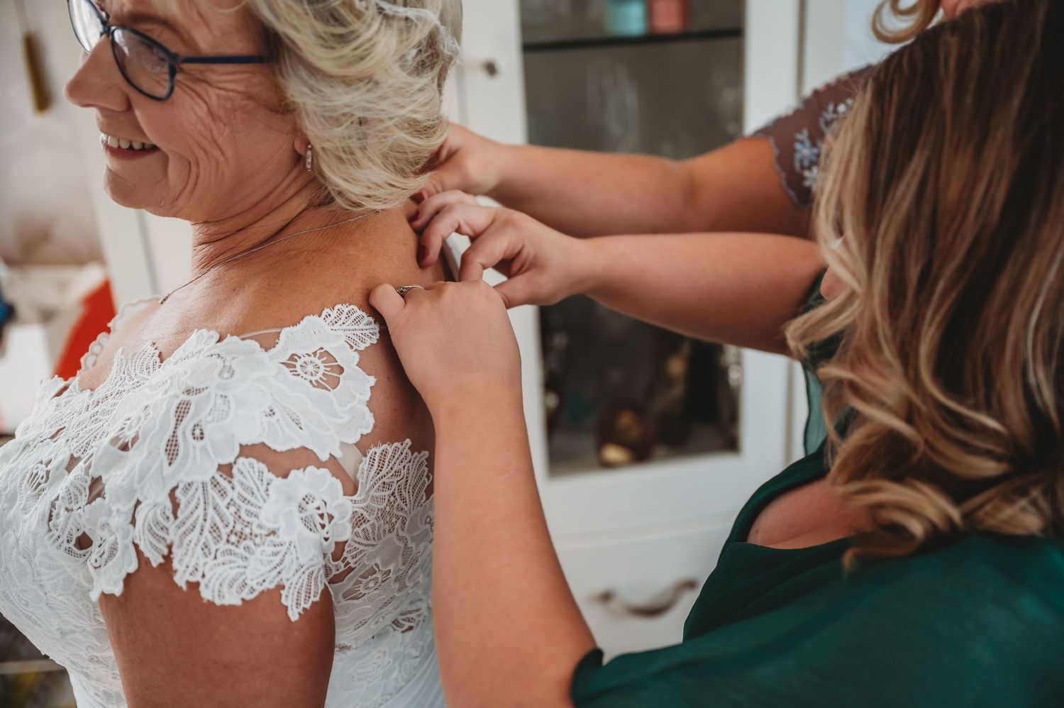 Close-up shot showing lace details of a white wedding dress being adjusted during bridal preparations.
