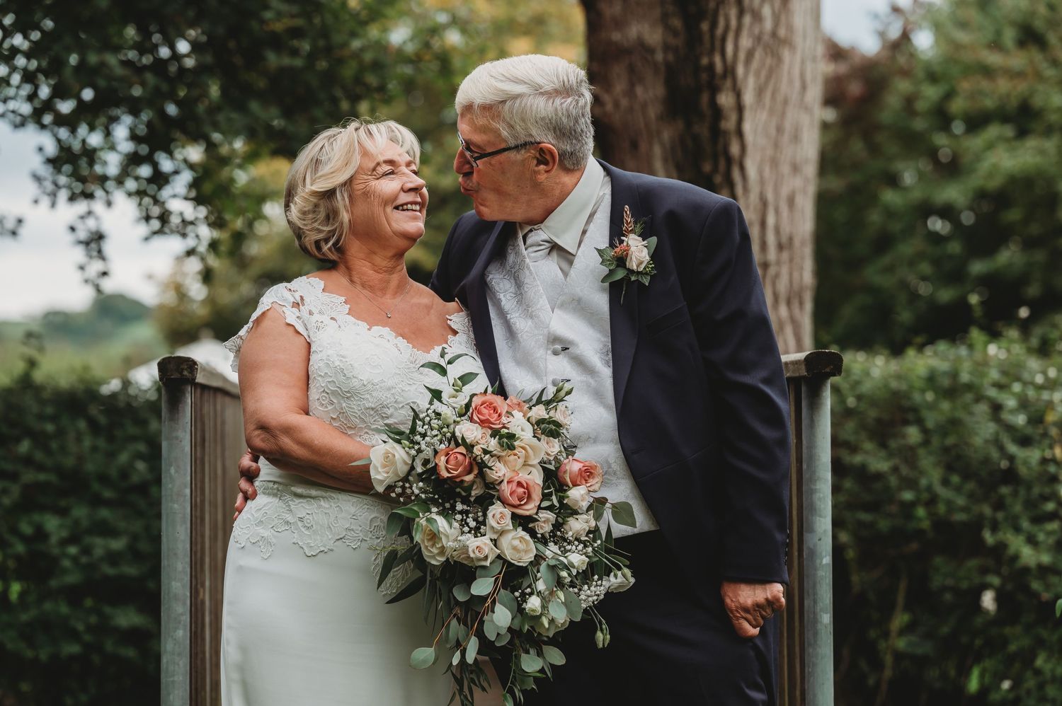A joyful elderly couple share a romantic moment on their wedding day, with the bride holding a beautiful bouquet.