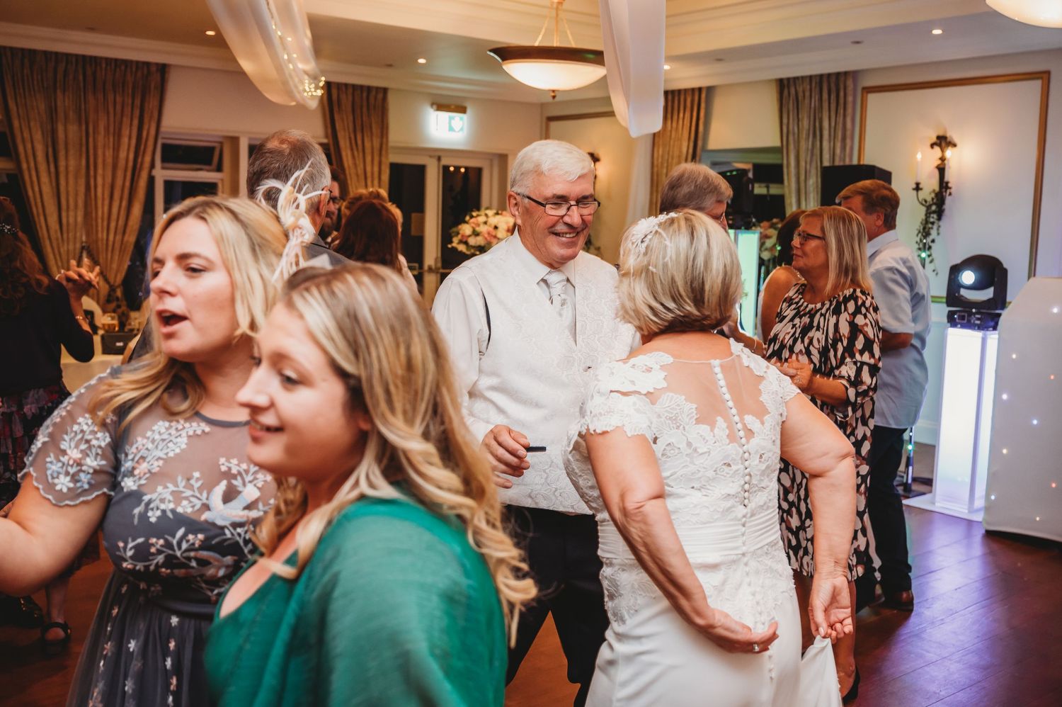 Wedding guests enjoying themselves on the dance floor during a lively reception celebration.