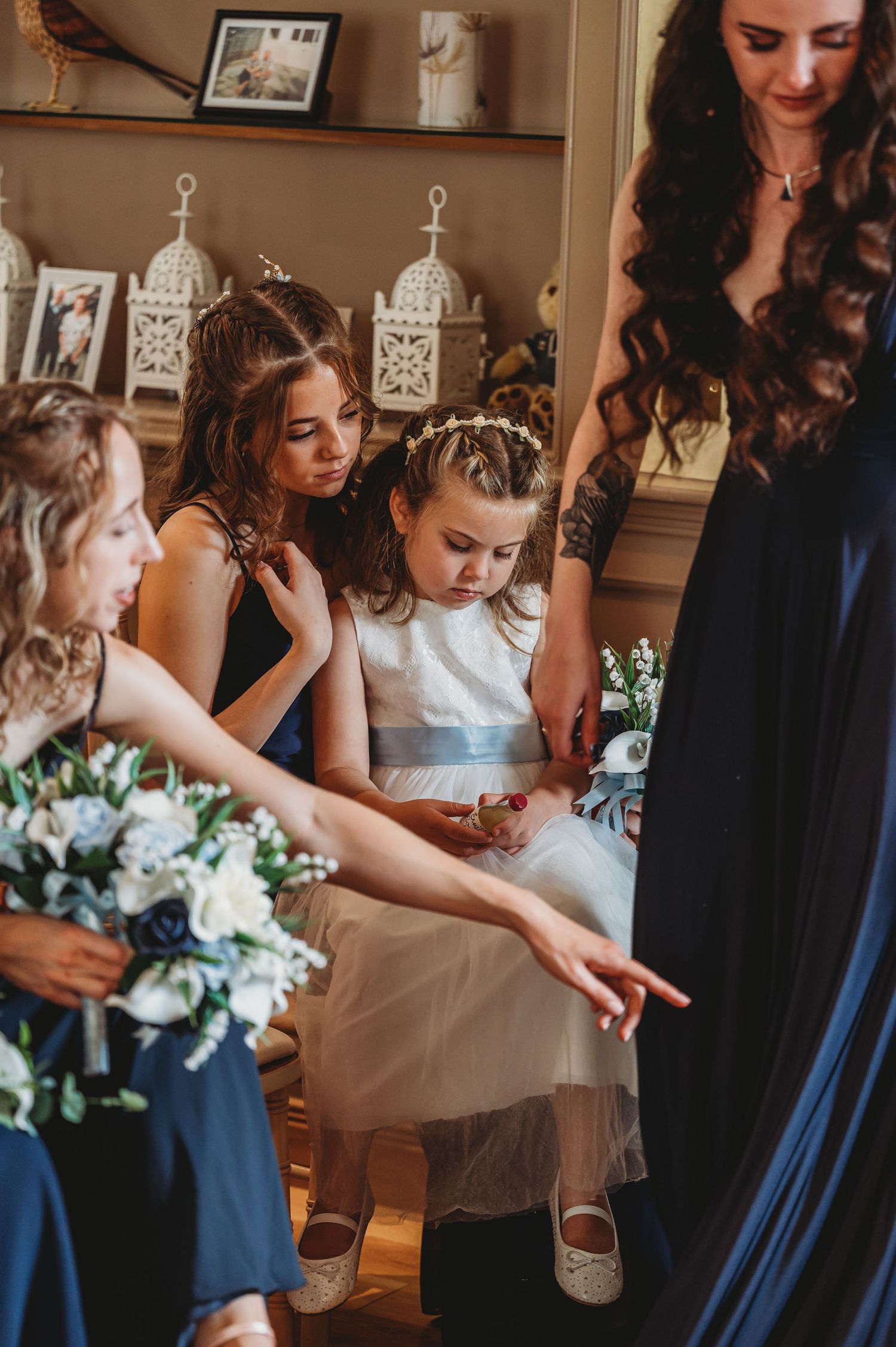Bridal party members gather around looking at something together while holding blue and white flower bouquets.