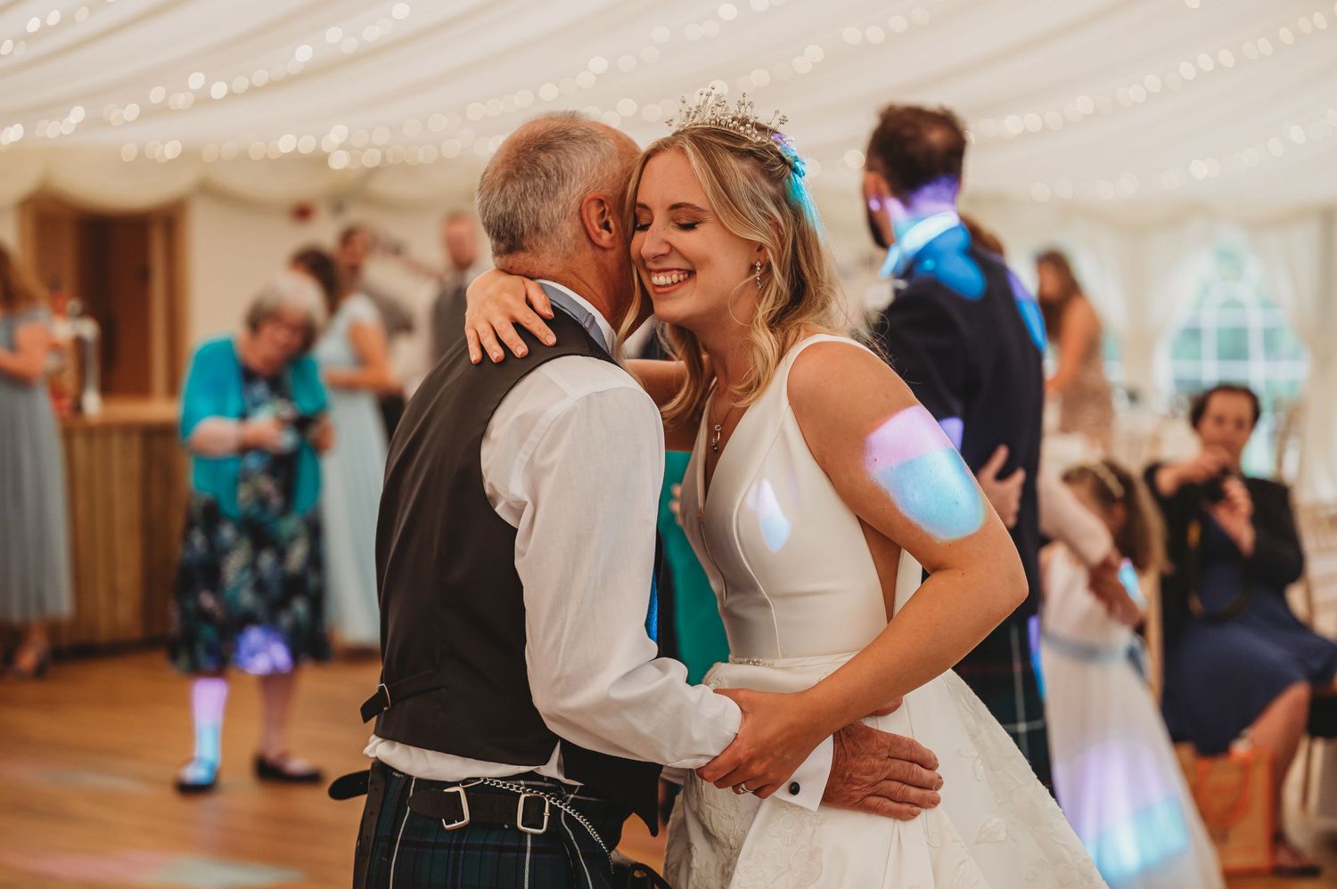 A joyful dance between lifelong partners at a wedding reception under a draped tent ceiling.