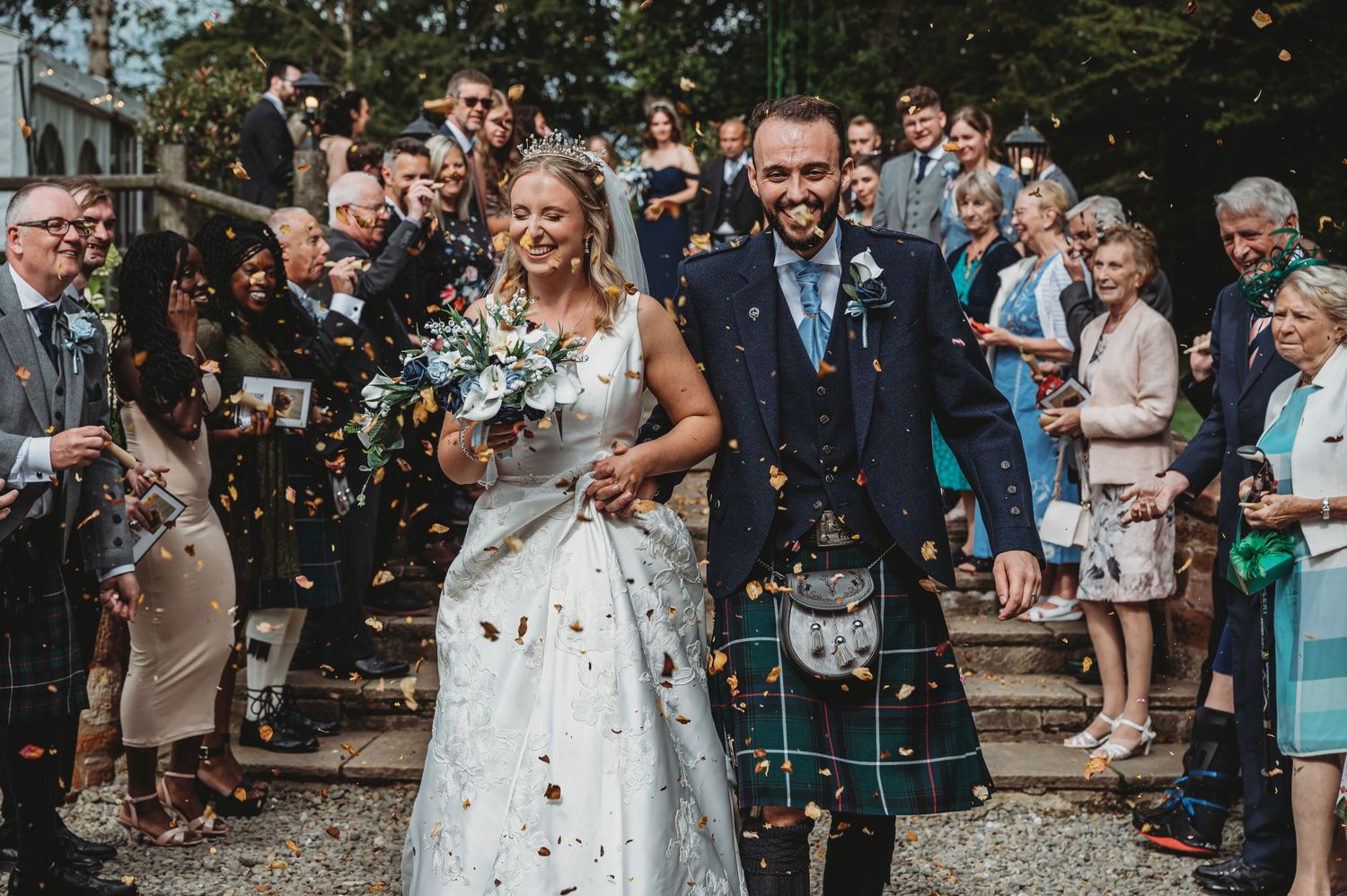 A couple celebrates their Scottish wedding day while guests shower them with confetti outside a church.