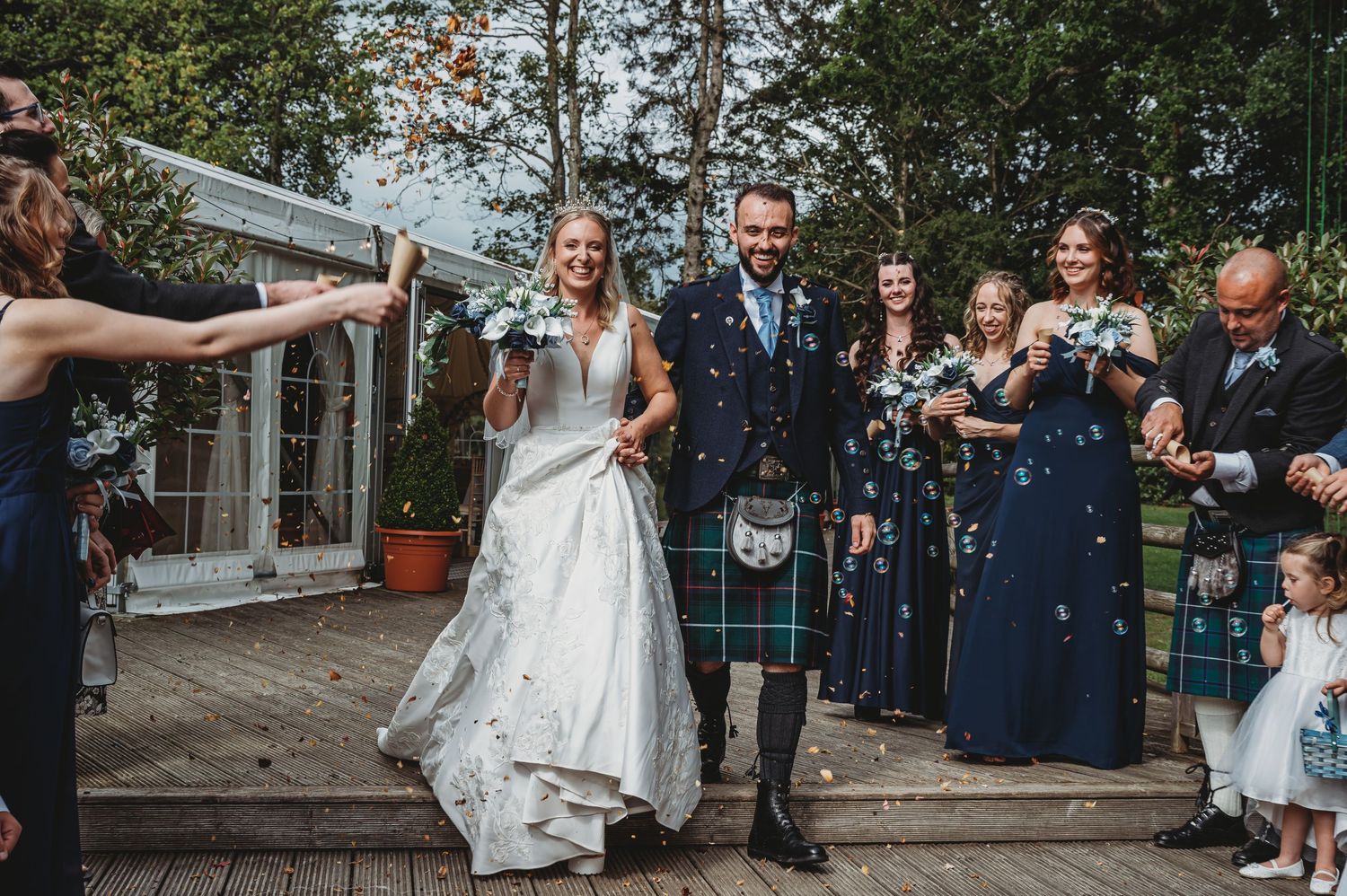 Wedding celebration outside with the couple and guests showered in confetti during a traditional Scottish ceremony.