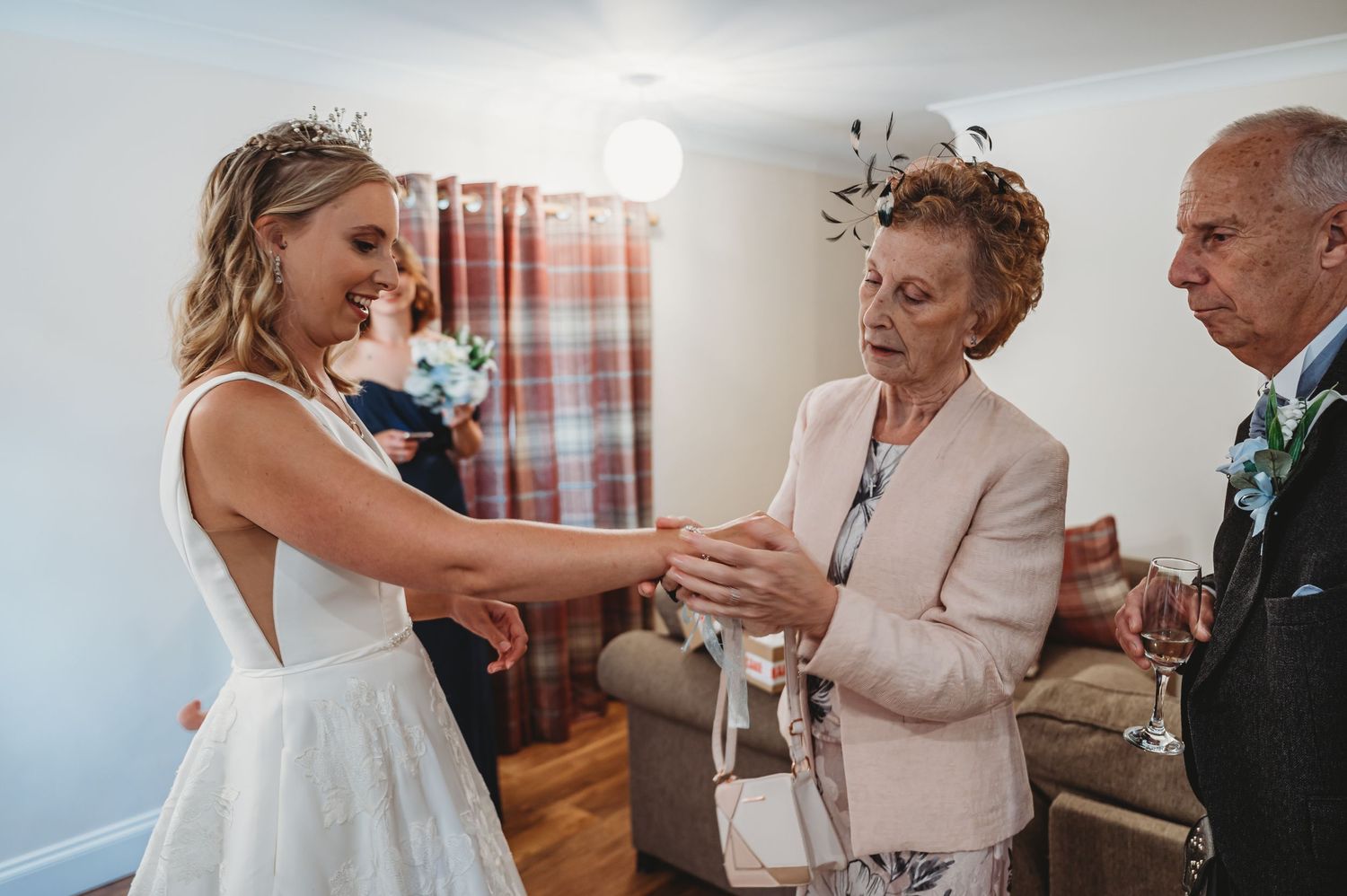 Three people share a joyful moment together during a wedding celebration in a warmly lit indoor setting.