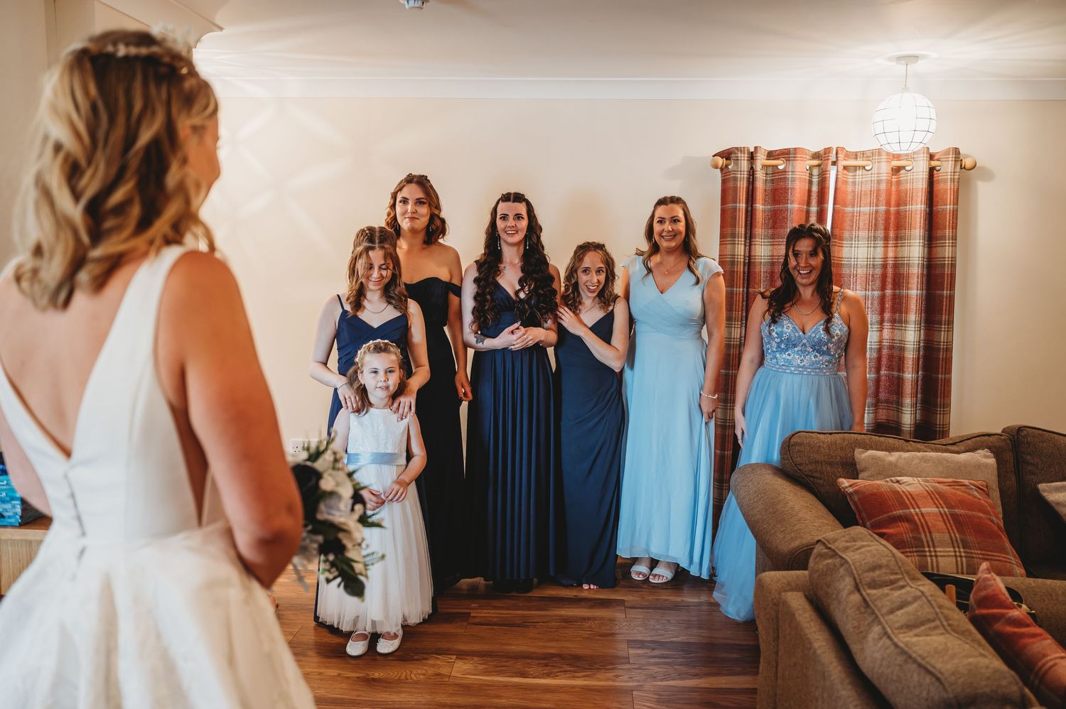Bridesmaids in flowing blue dresses gather together in a room as they prepare for the wedding ceremony.