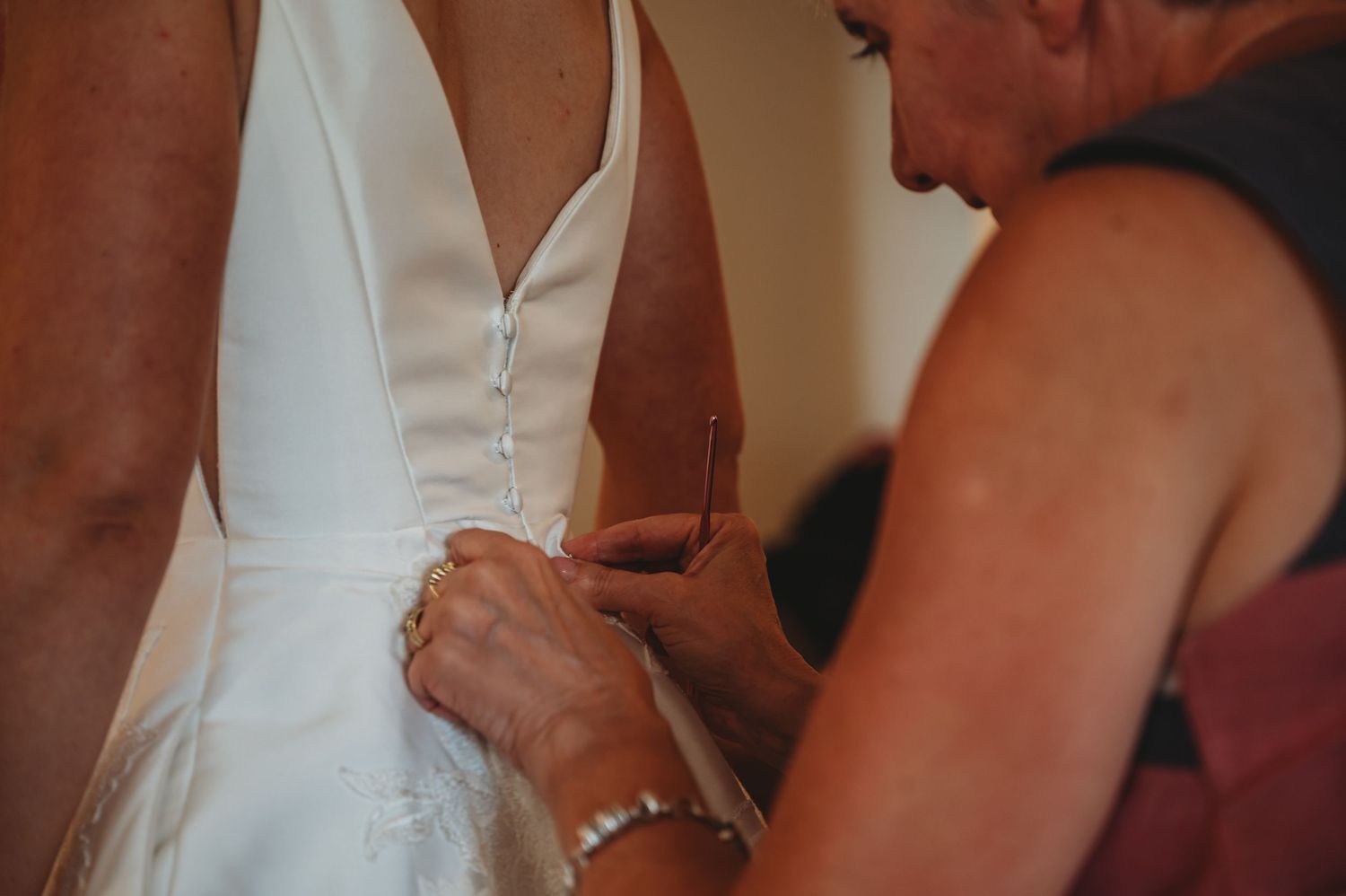 A close-up view of hands adjusting a white wedding dress, showing careful attention to detail during preparations.