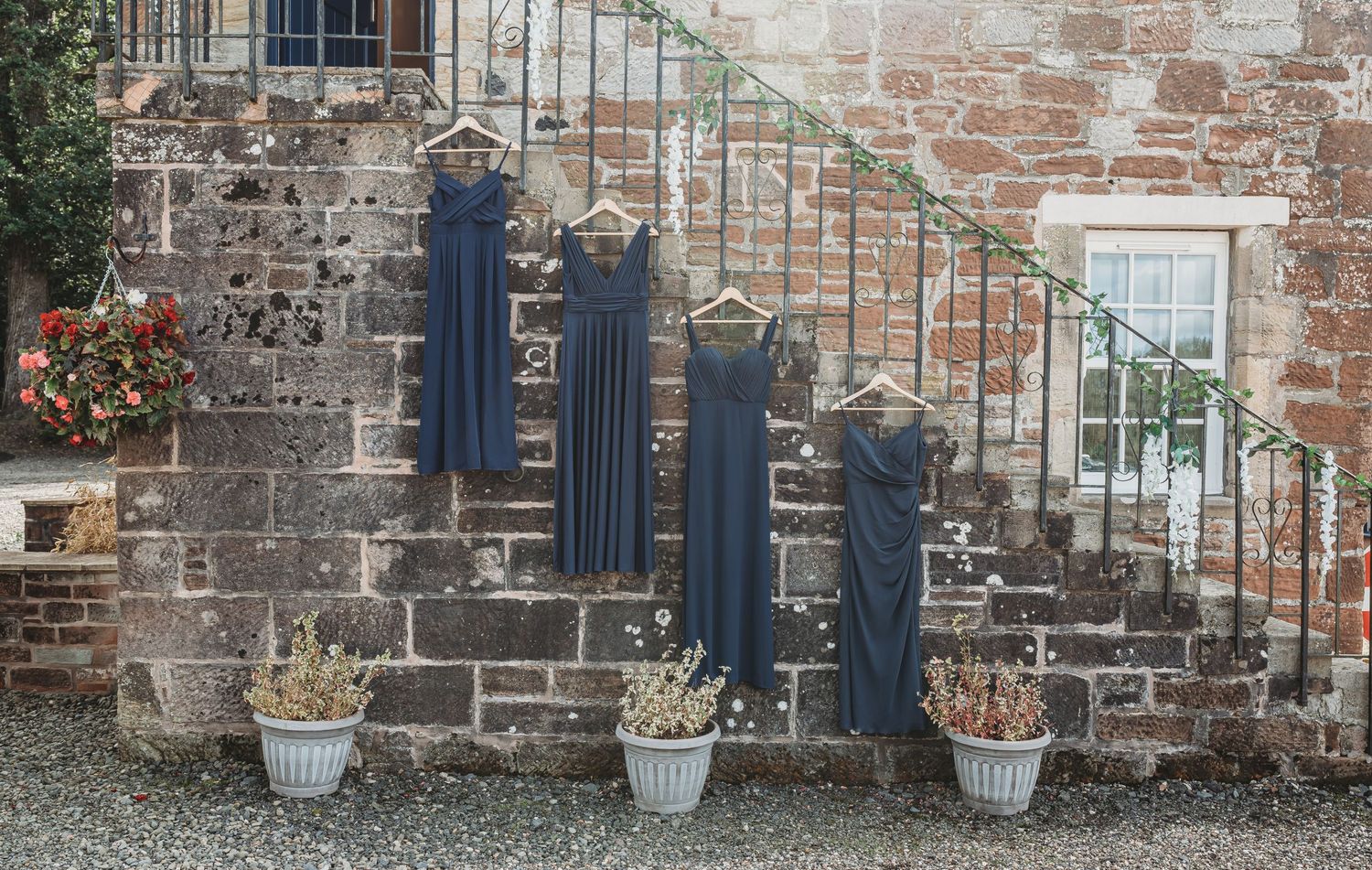 Three blue-painted posts line up along garden stone steps with potted plants at an old stone wall.