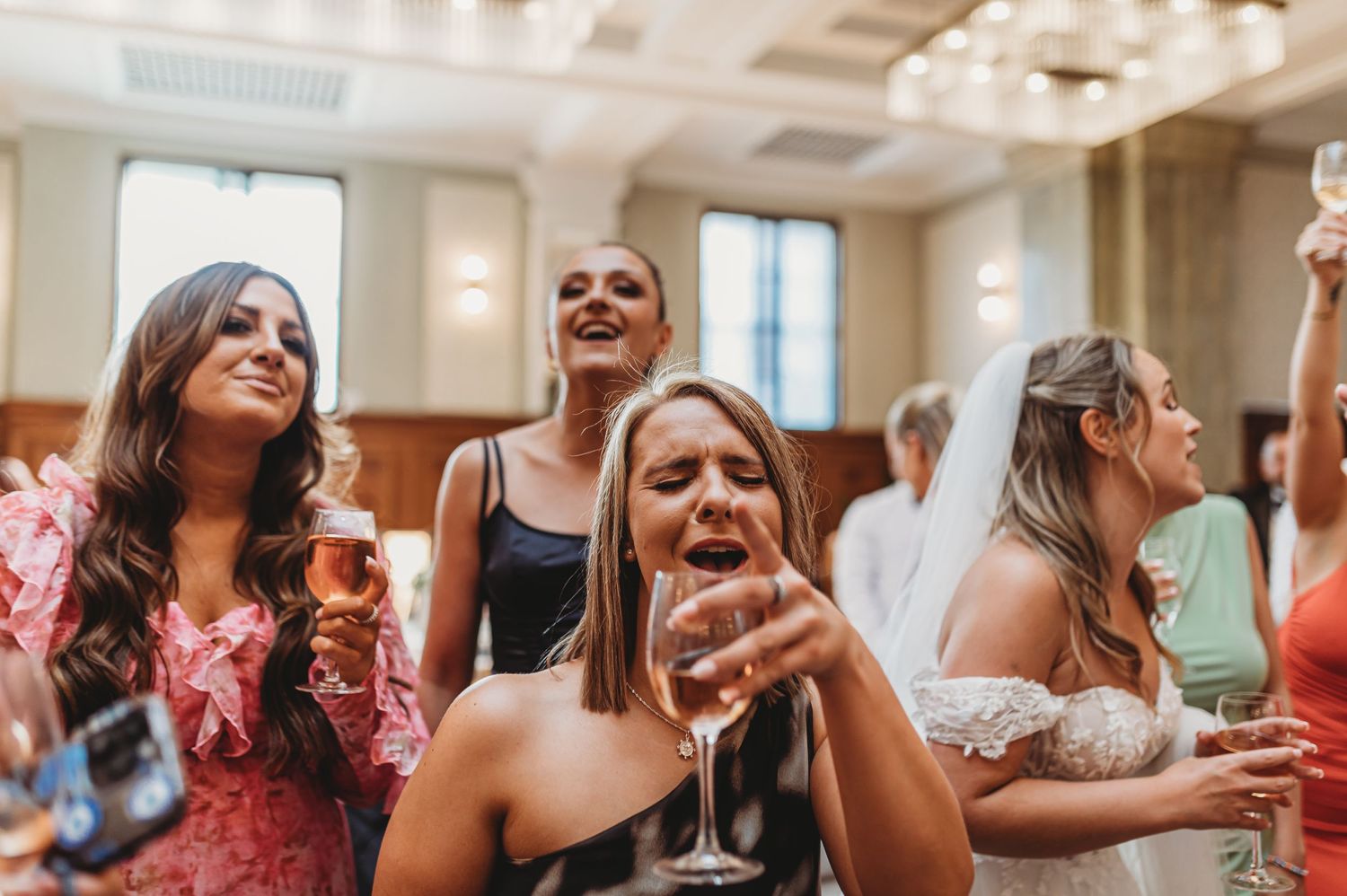 Wedding guests dancing and celebrating with drinks at reception.