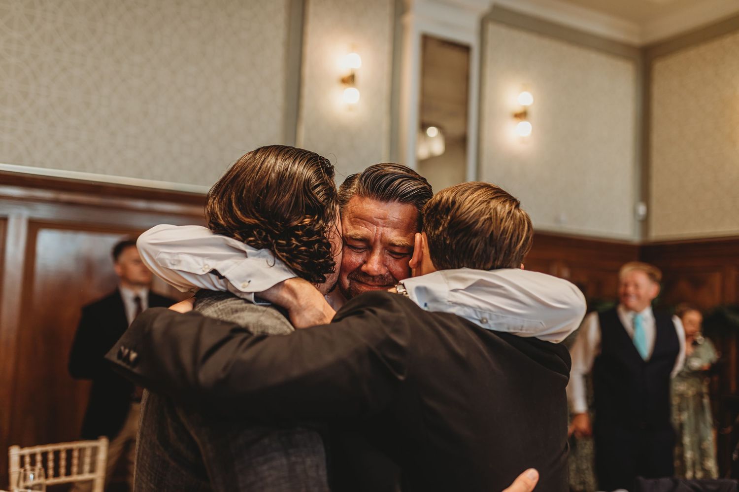 Emotional group hug captured during wedding celebration.