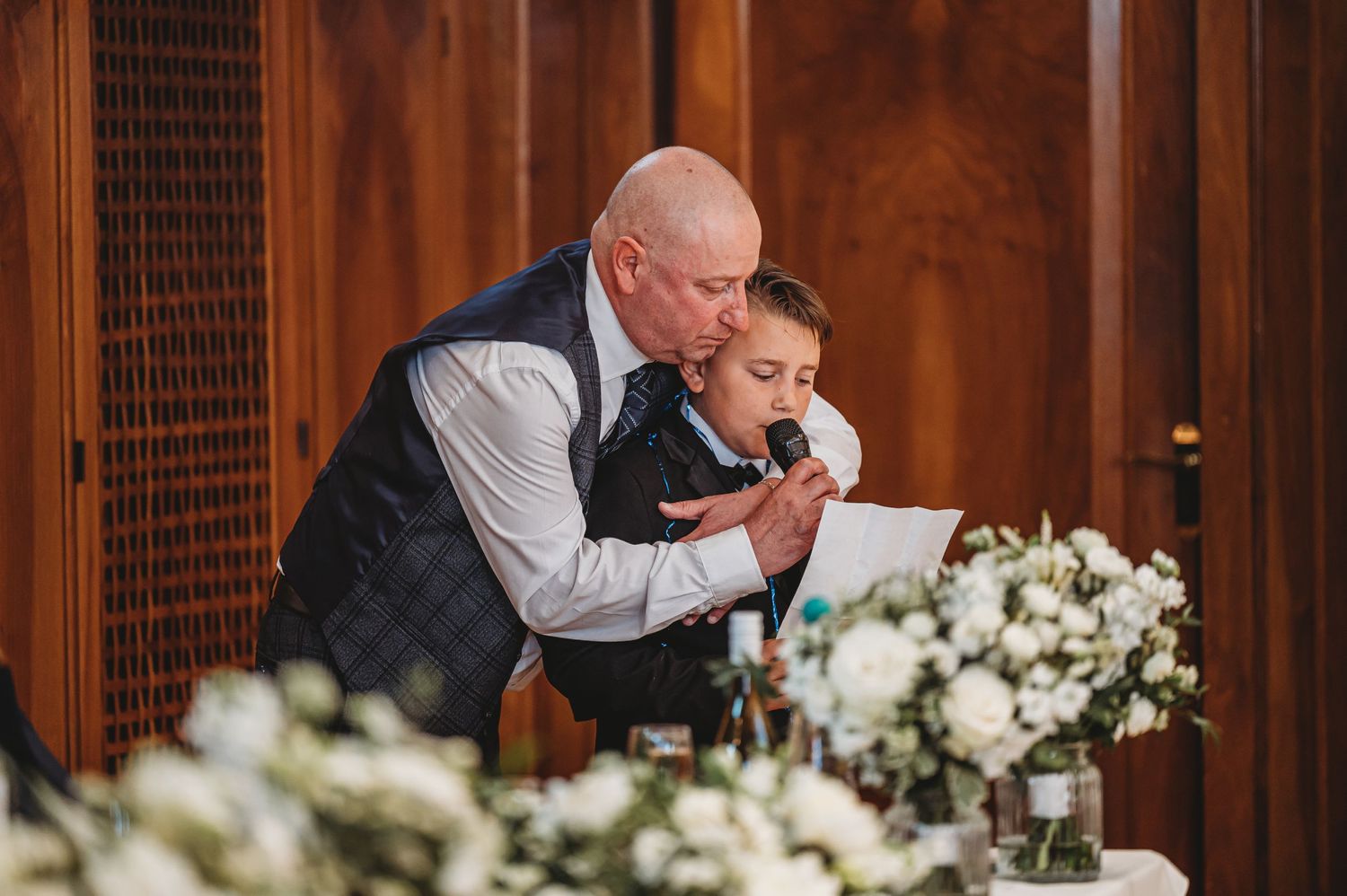 A young boy and older gentleman share a moment while reading during the wedding reception.