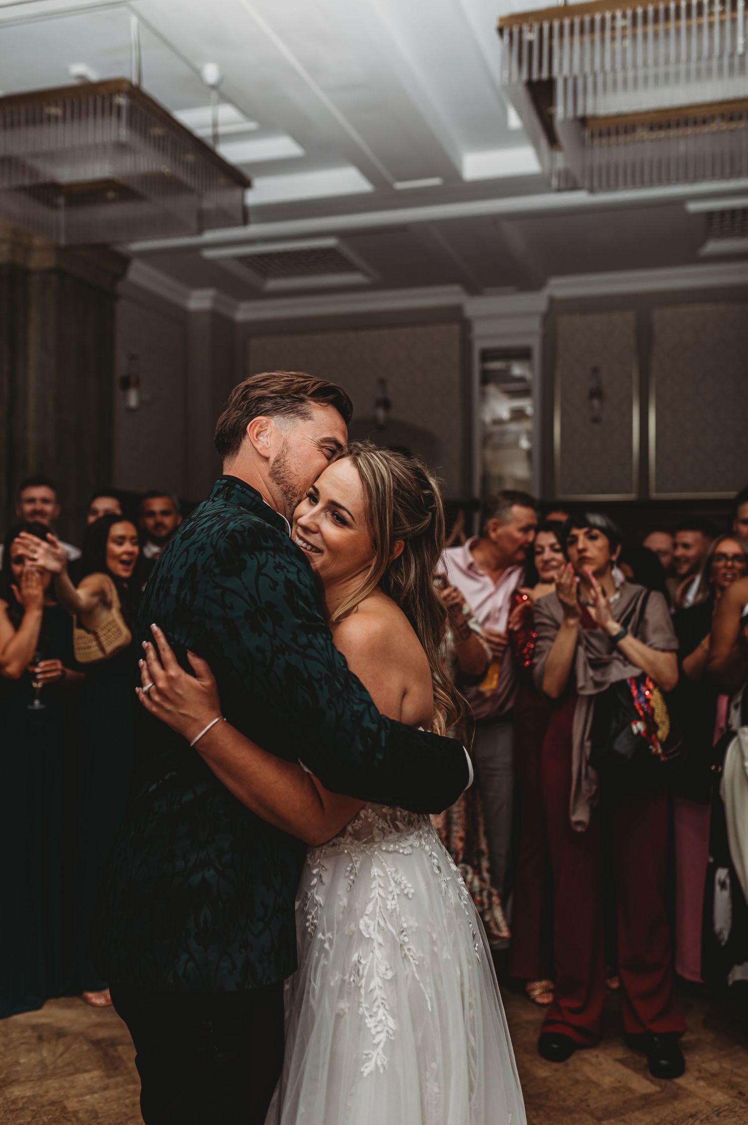 A romantic embrace during the wedding first dance surrounded by guests.