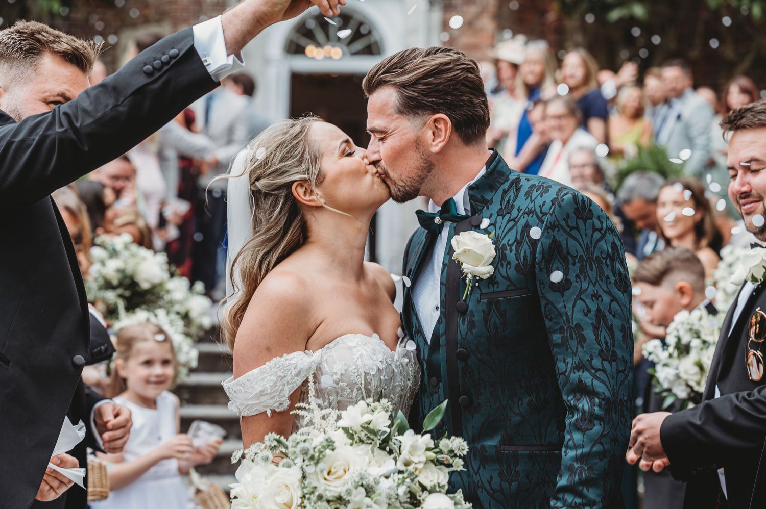 Wedding celebration moment with confetti and cheering guests outside historic venue.