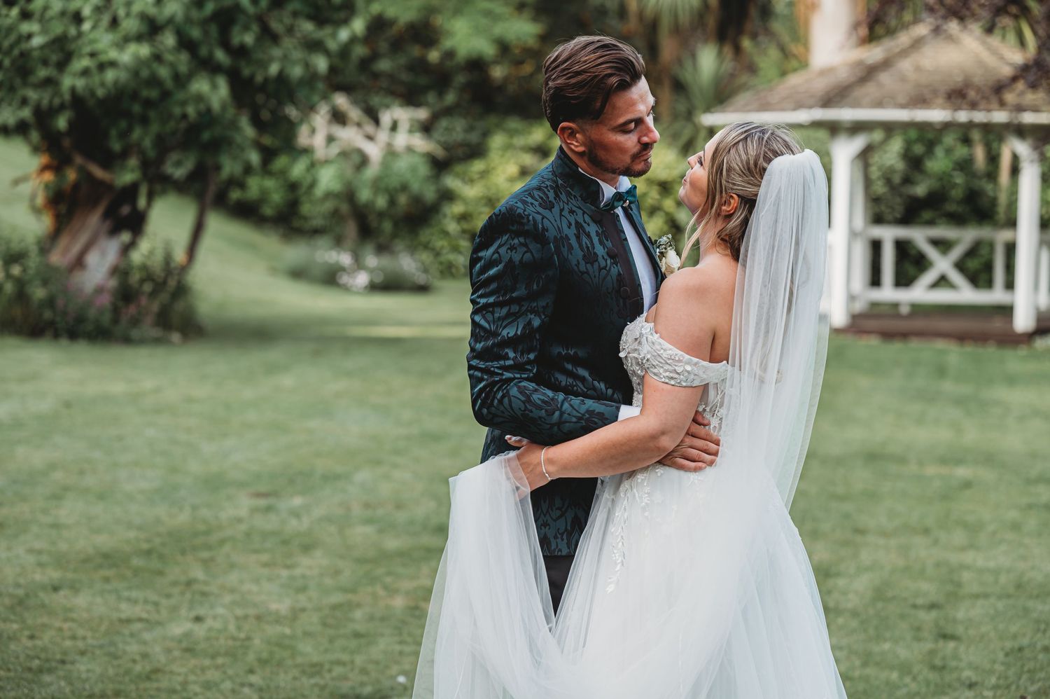 Wedding couple sharing an intimate moment in a garden setting during golden hour.