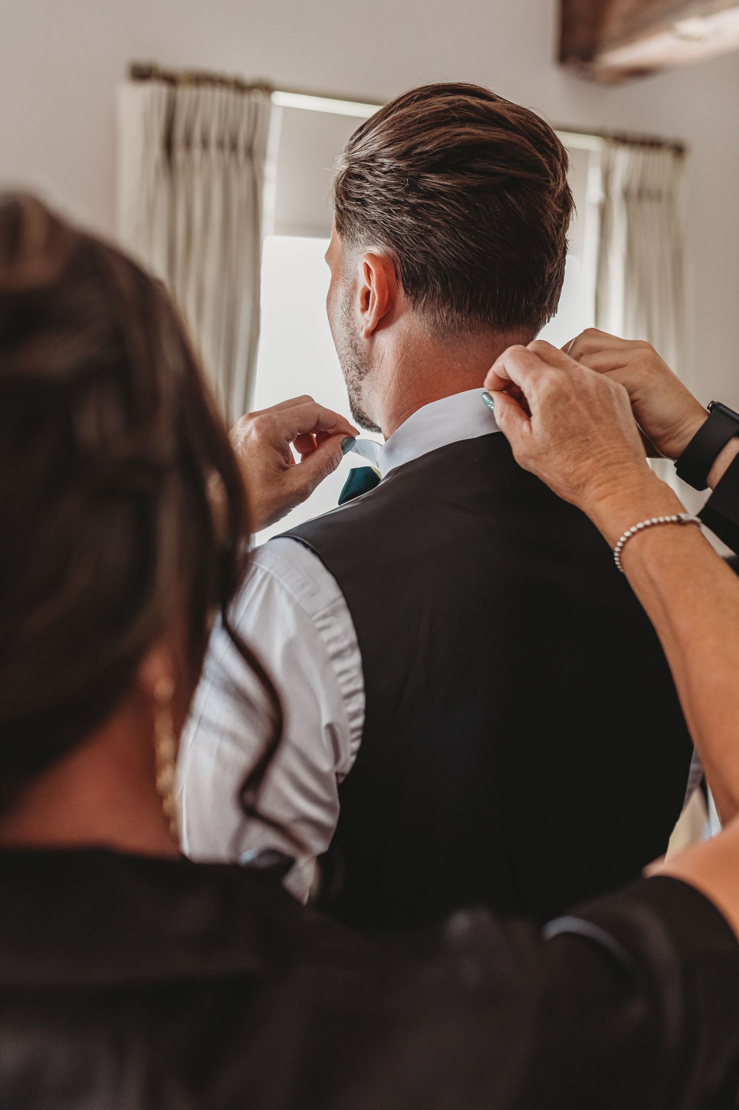Adjusting tie and collar details on groom's formal attire.