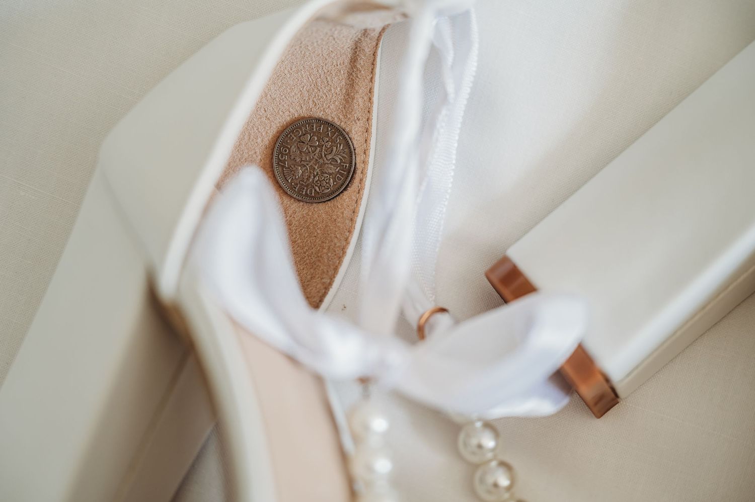 Elegant white bridal shoe with pearls and metallic details.