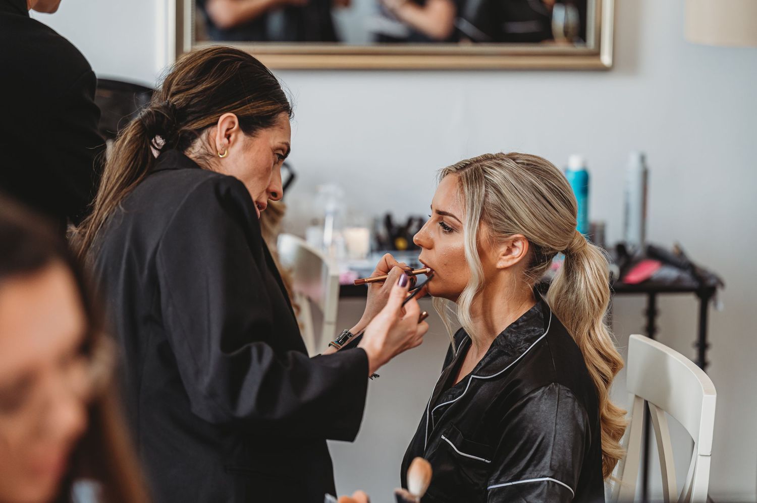 Makeup artist applying lipstick during wedding day preparations.