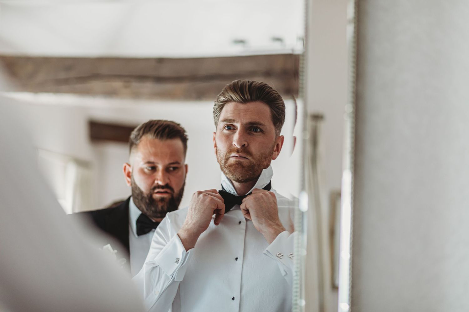 Getting ready scene showing a bowtie adjustment in a mirror reflection.