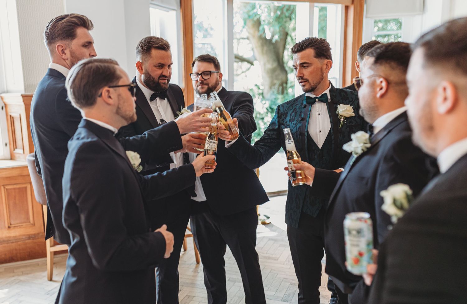 Group of groomsmen raising glasses for a celebratory toast at a wedding event.