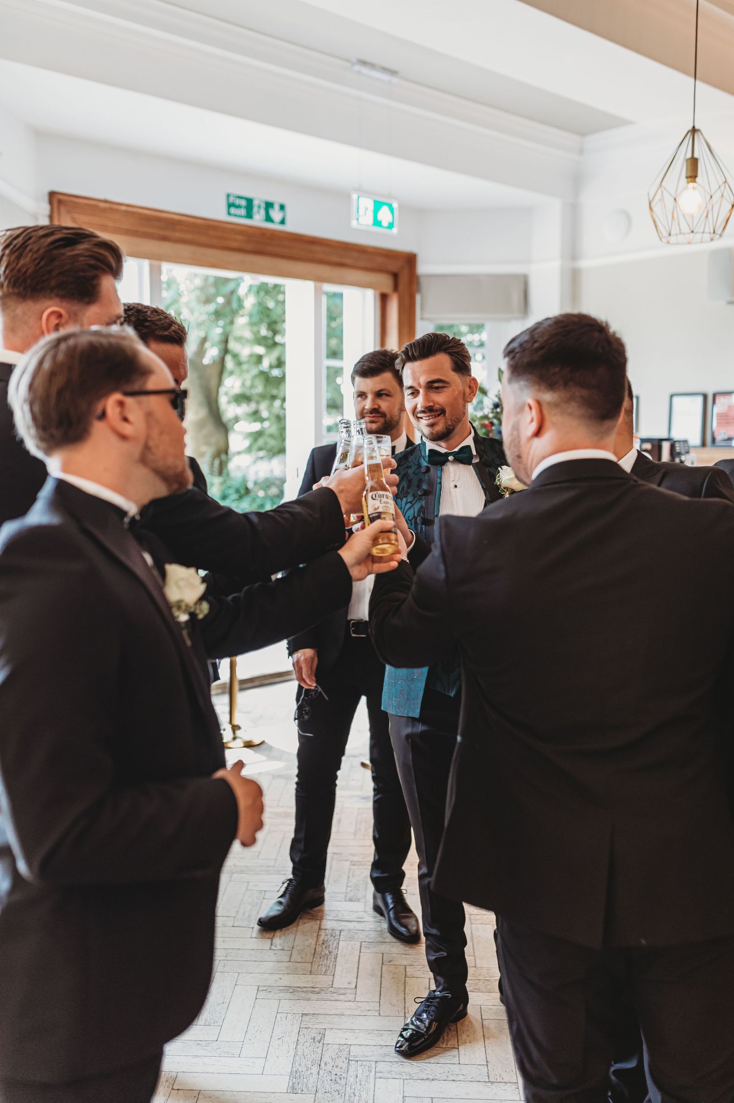 Groomsmen in black tuxedos toasting with champagne glasses at a wedding celebration.