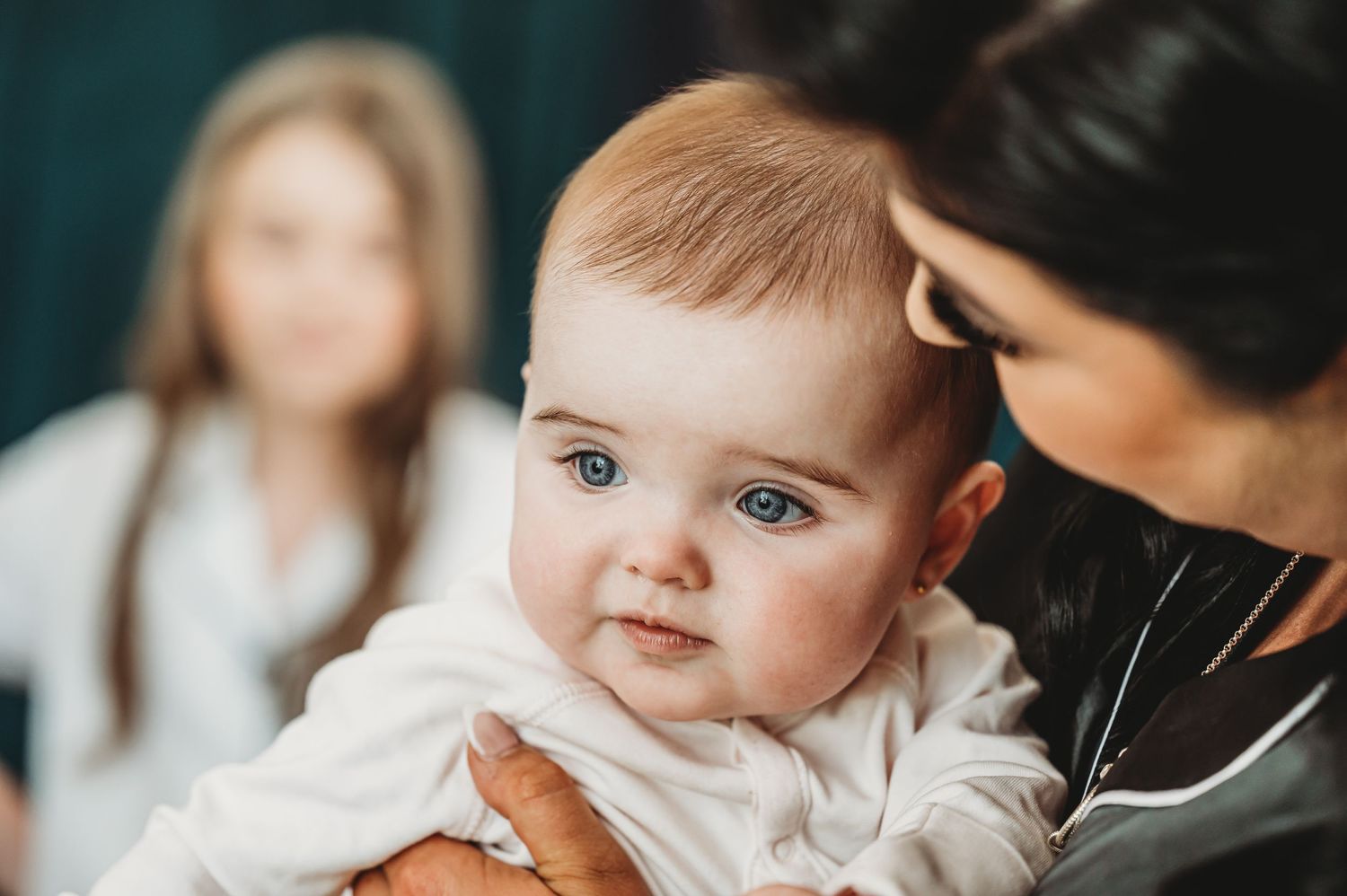 A tender moment with a baby in white clothing being held.