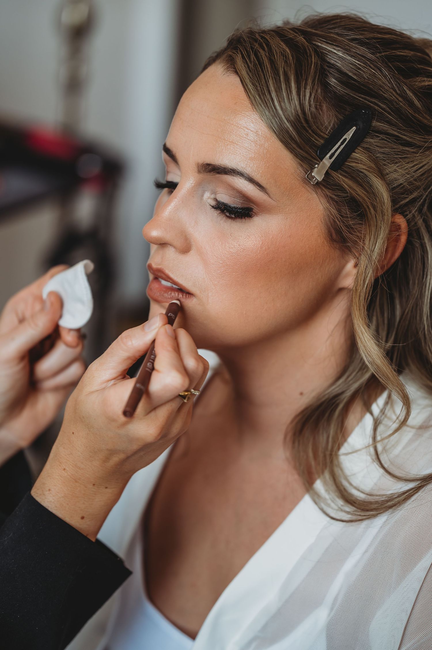 Professional makeup application showing detailed lip color application in progress.