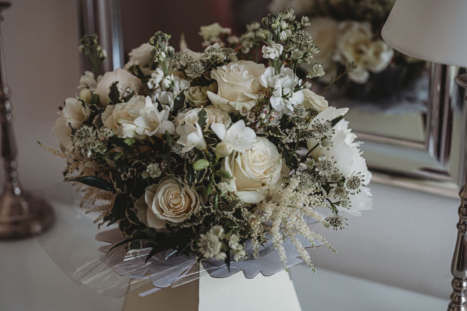 A close-up of a romantic white rose and baby's breath wedding bouquet arrangement.
