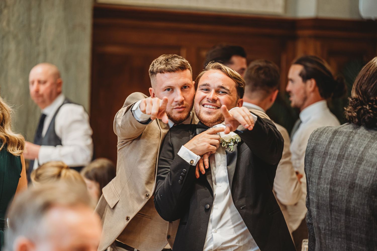 Wedding guests pointing and laughing during reception celebrations.