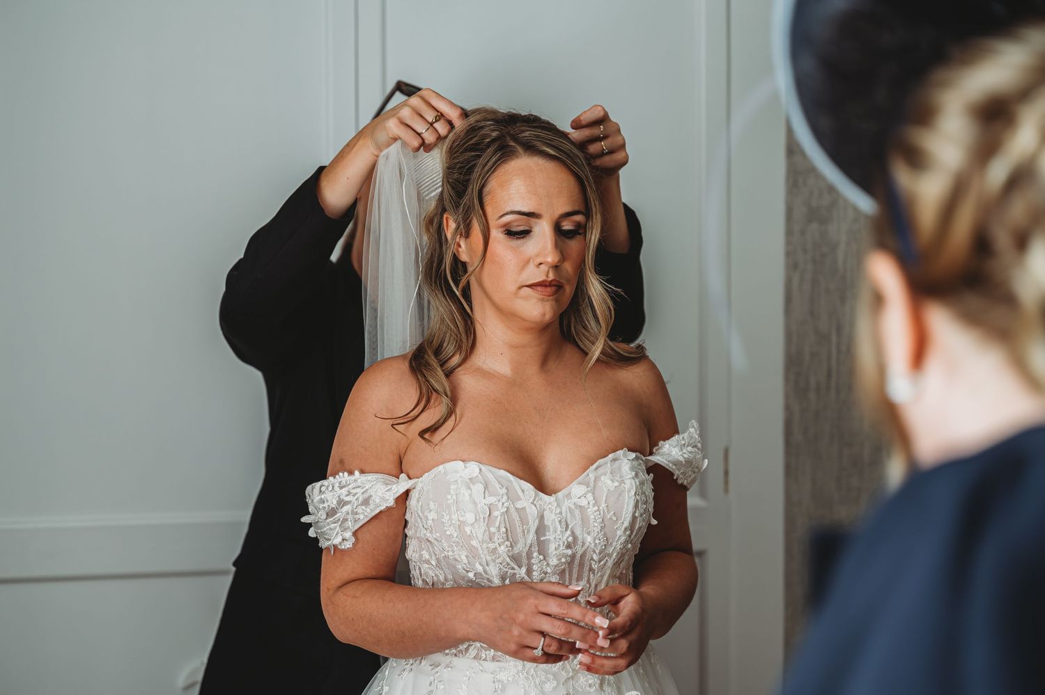 Behind-the-scenes moment of bride getting ready with veil being adjusted.