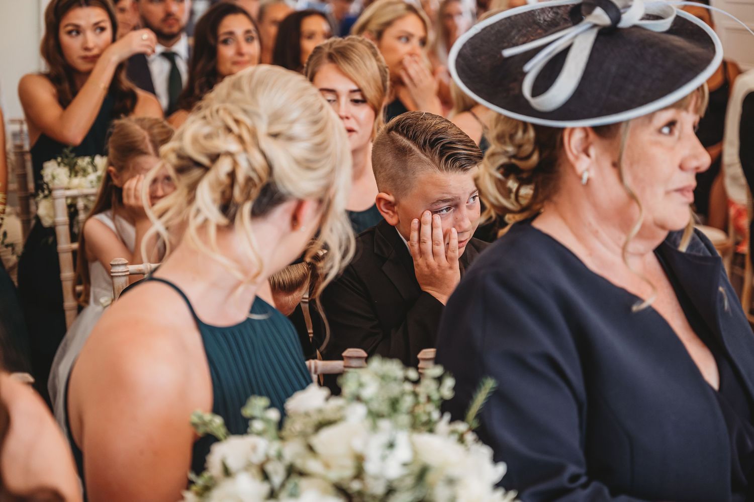 Wedding guests react emotionally during ceremony in elegant venue.