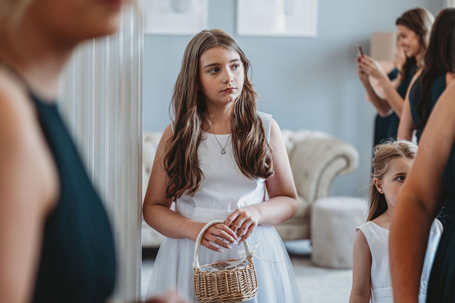 Young attendee in white dress holding a woven purse at formal event.