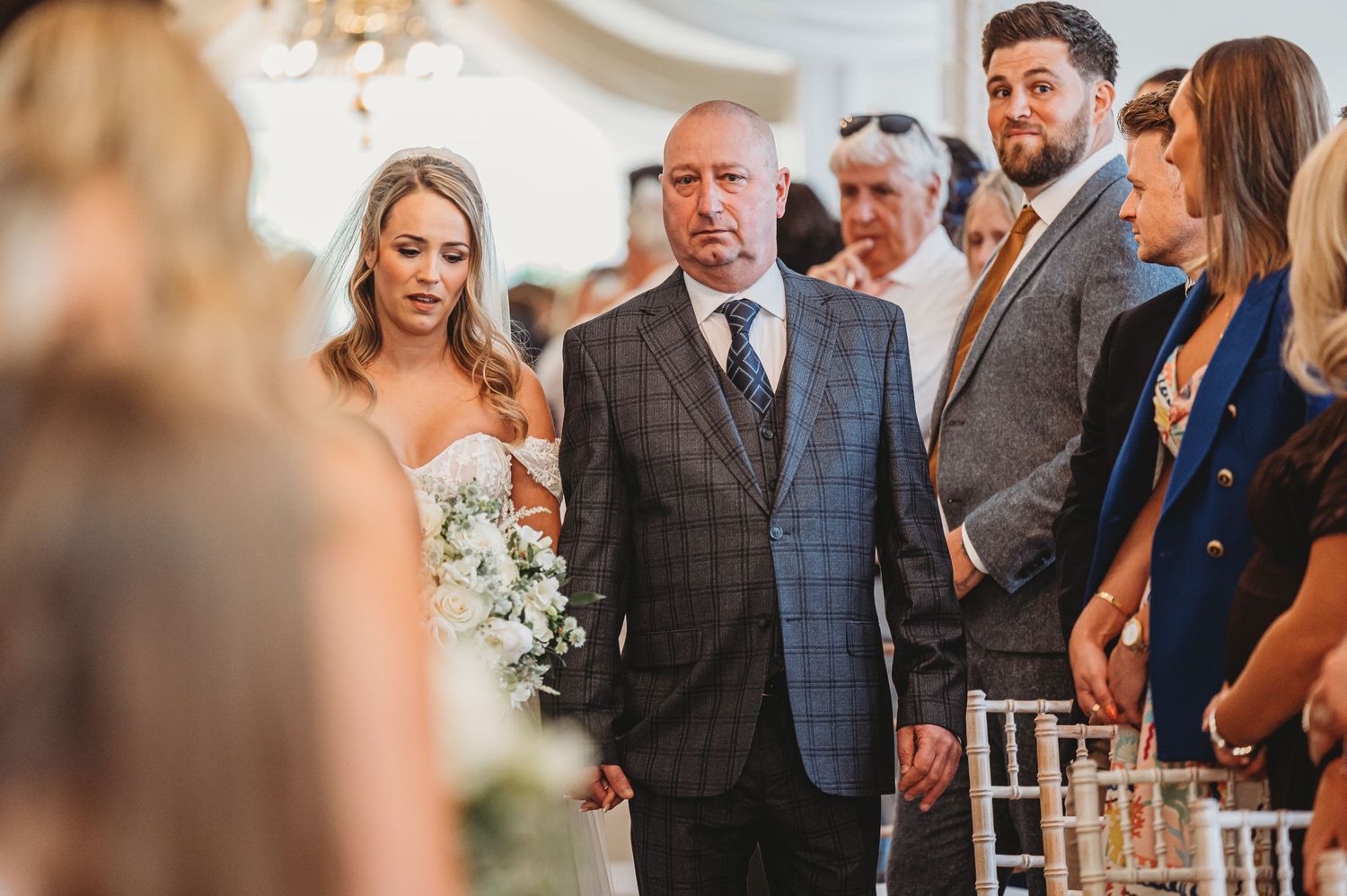 Wedding ceremony gathering with guests in formal attire and elegant floral arrangements.