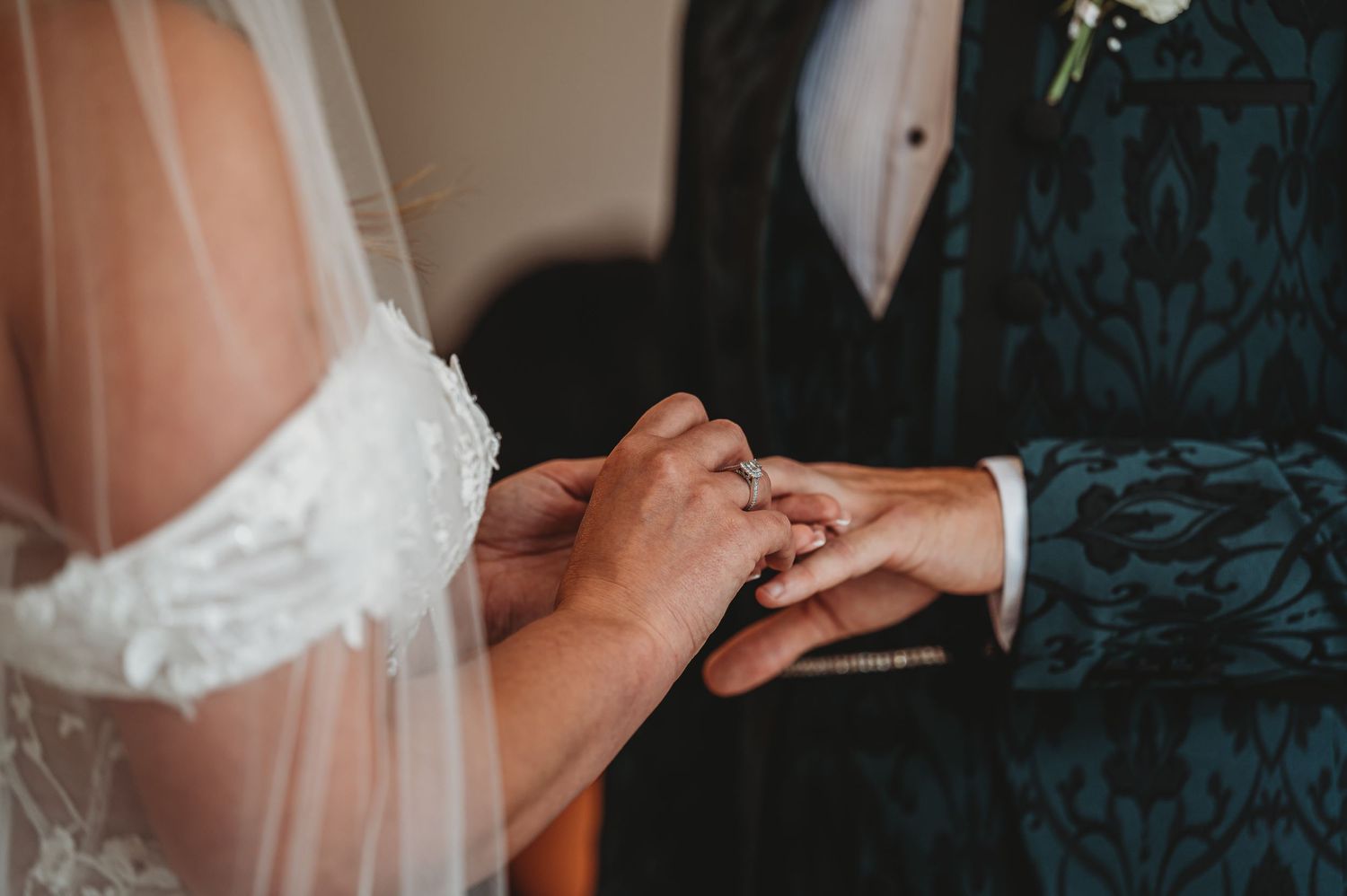 Close-up of hands exchanging wedding rings during ceremony.