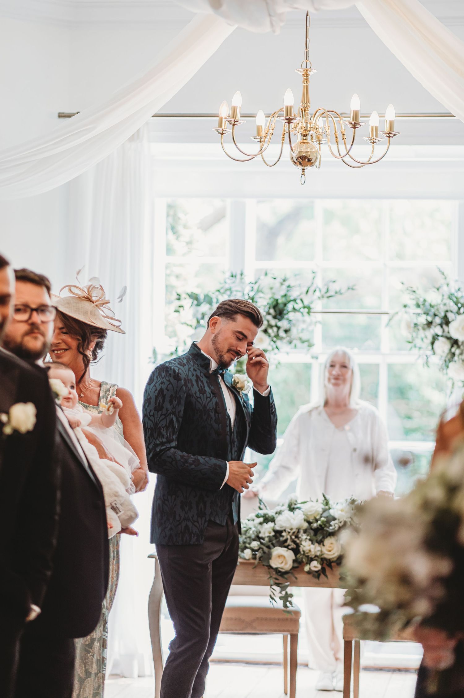 Elegant indoor wedding venue with chandelier and white fabric draping.
