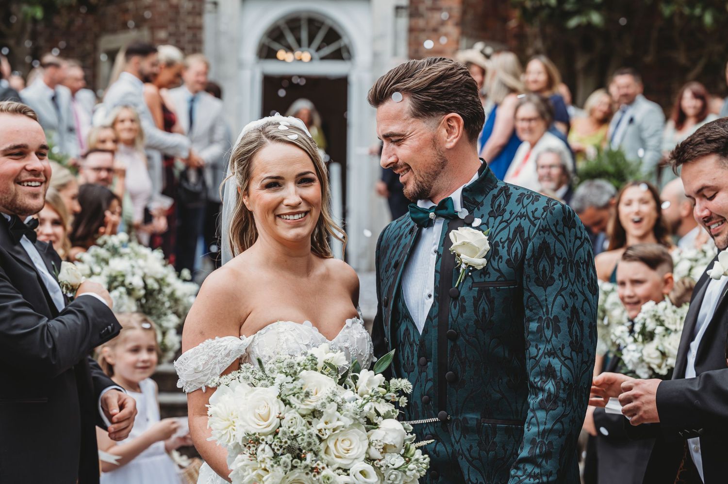Wedding couple shares joyful moment surrounded by guests during outdoor ceremony.